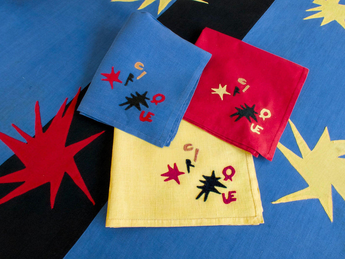 Assorted Porthault ‘Cirque’ linens showing vivid mid-century palette of red, yellow, blue, and black with abstract motifs.