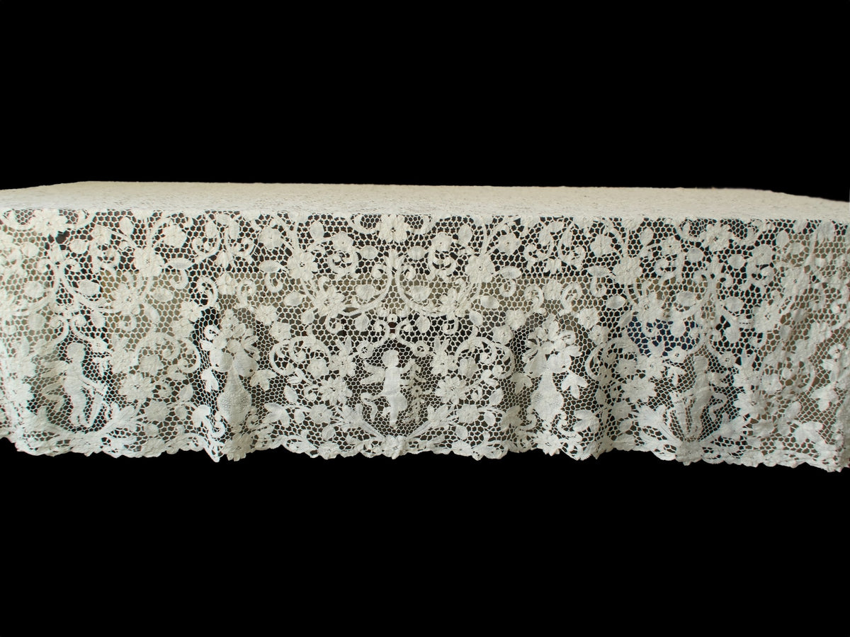 Side view of vintage handmade bobbin lace tablecloth highlighting the repeating cherub and floral design.
