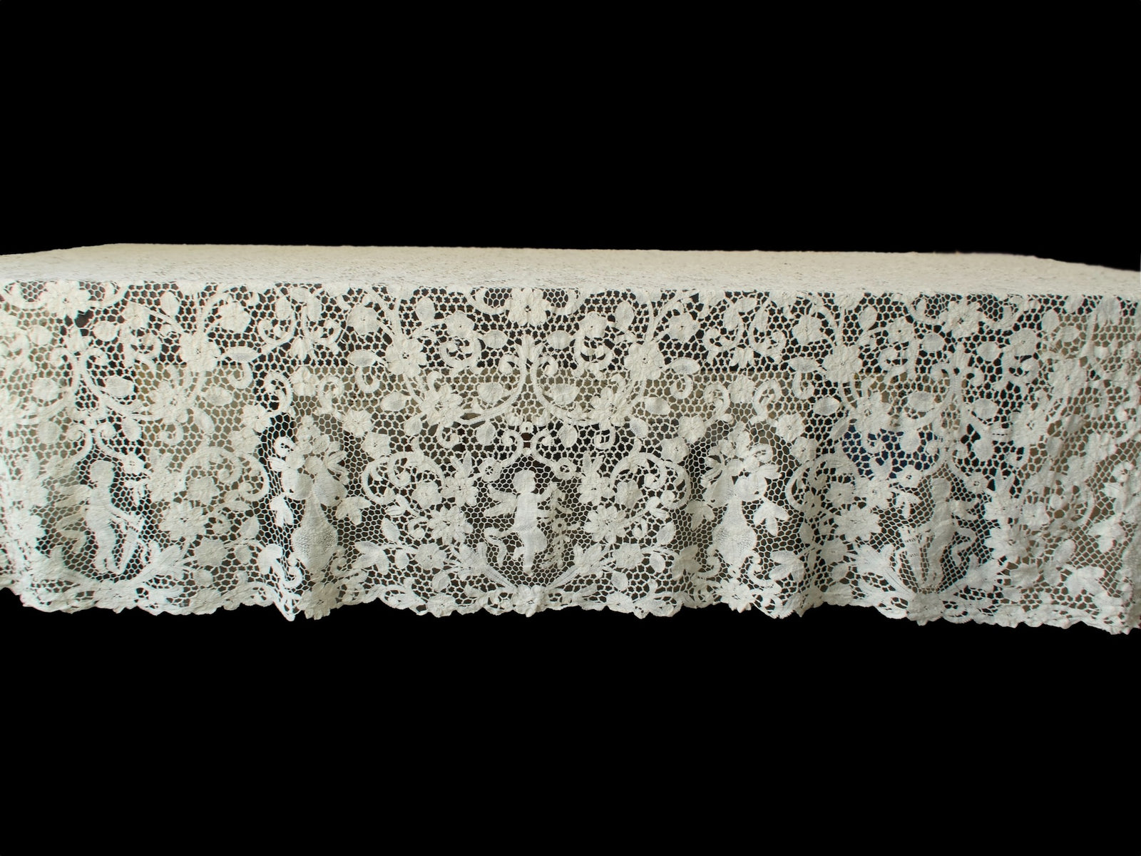 Side view of vintage handmade bobbin lace tablecloth highlighting the repeating cherub and floral design.