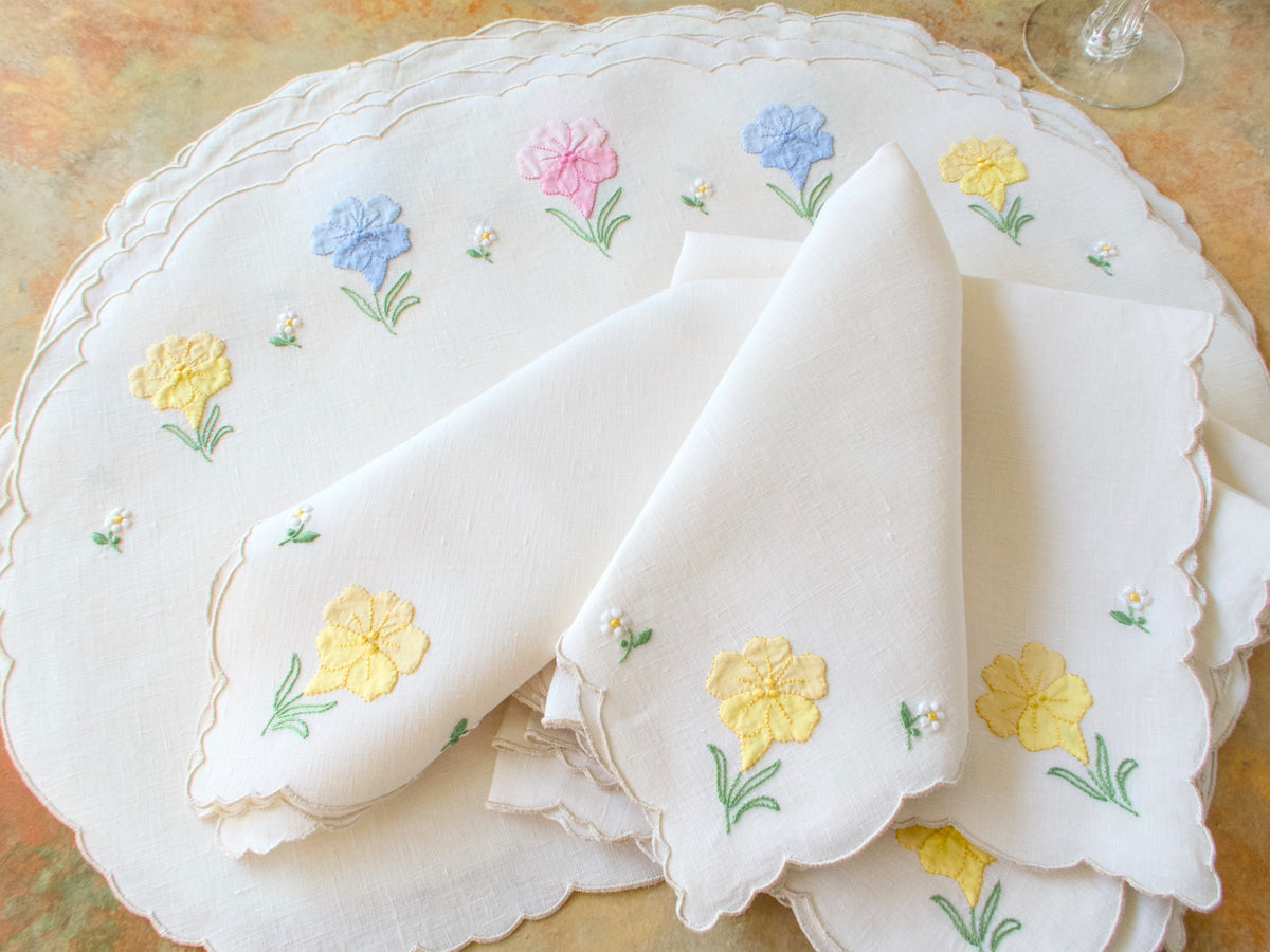 Vintage Madeira oval placemats with napkins showing hand embroidered spring flowers on natural linen with scalloped edge.