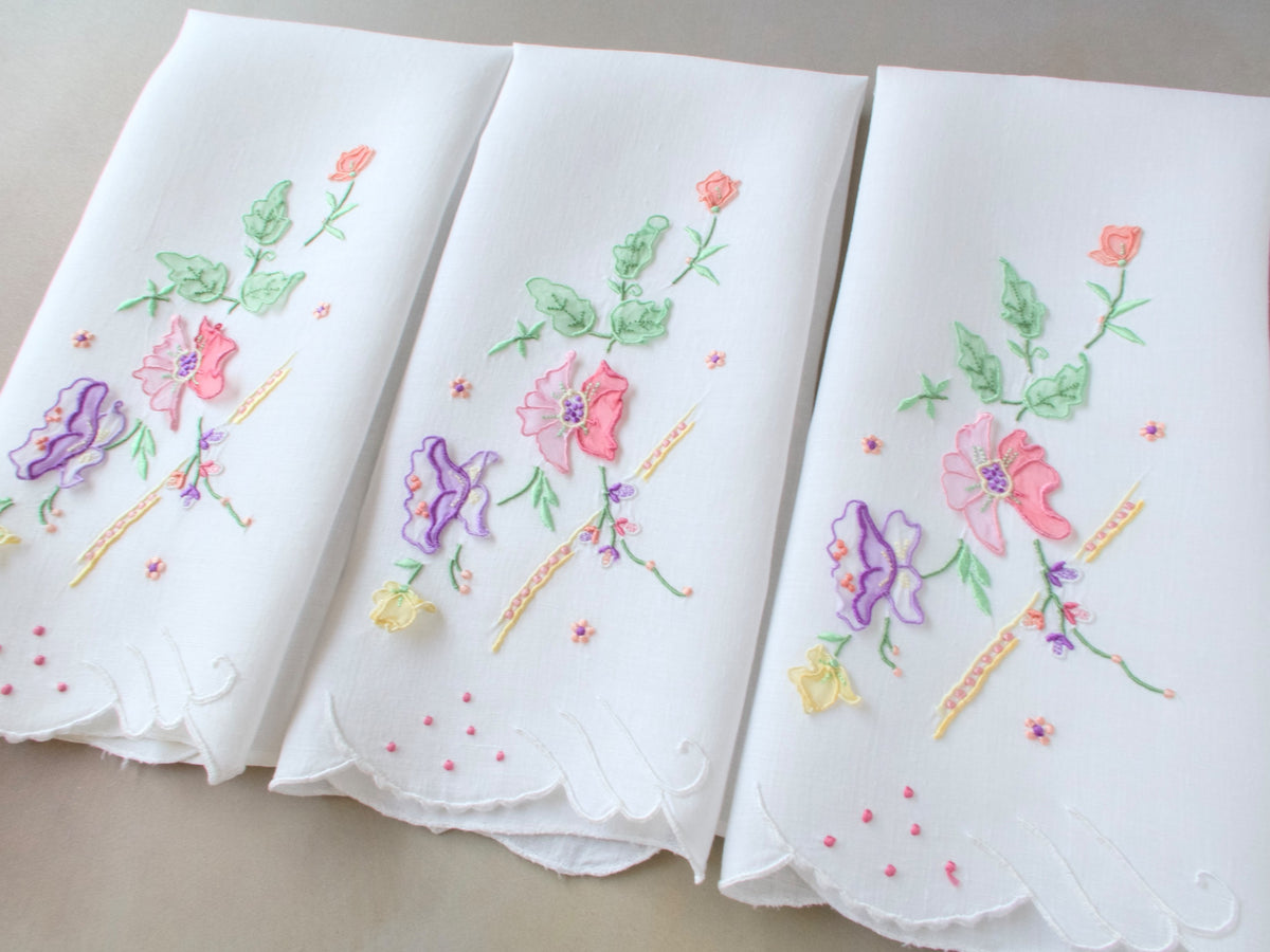Vintage Madeira embroidered guest towels with scalloped edges and dimensional trembler flower motifs in soft spring colors.