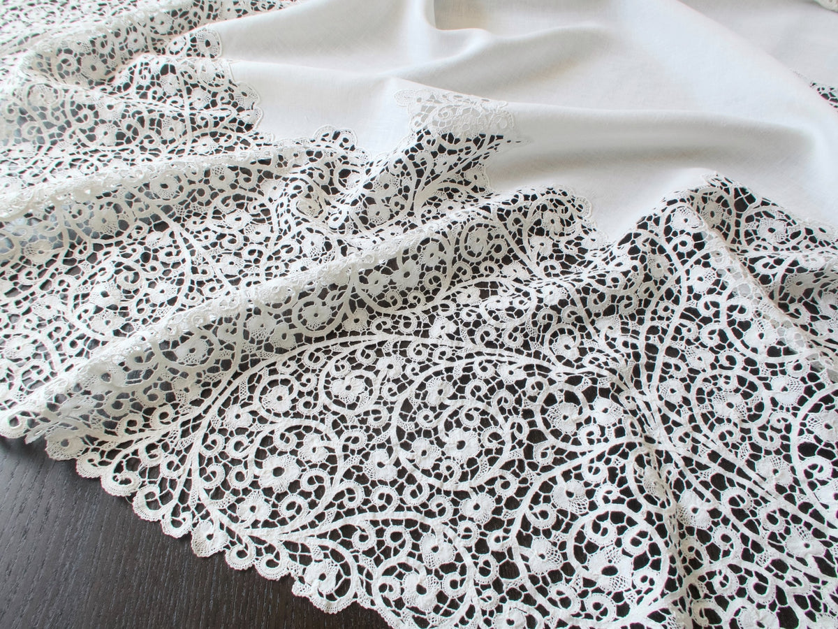 Close-up of the handmade Cantù lace on a vintage Italian round tablecloth.