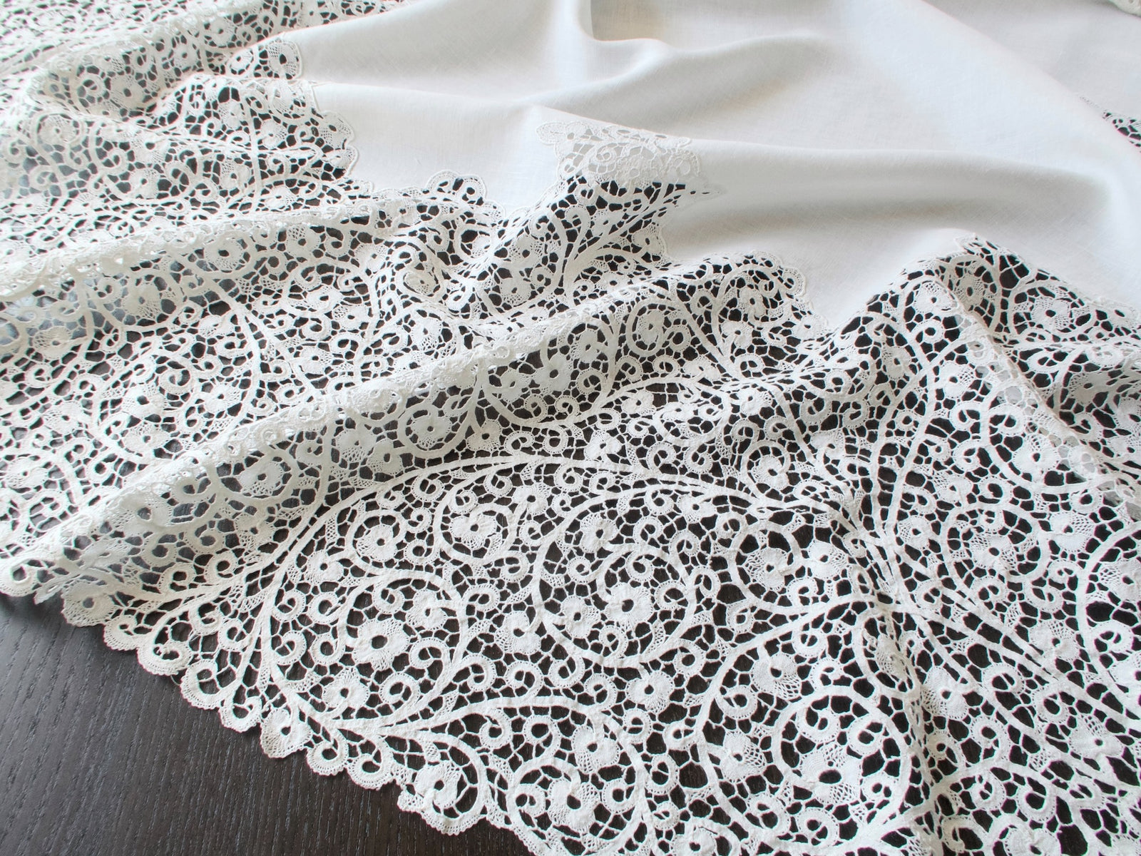 Close-up of the handmade Cantù lace on a vintage Italian round tablecloth.