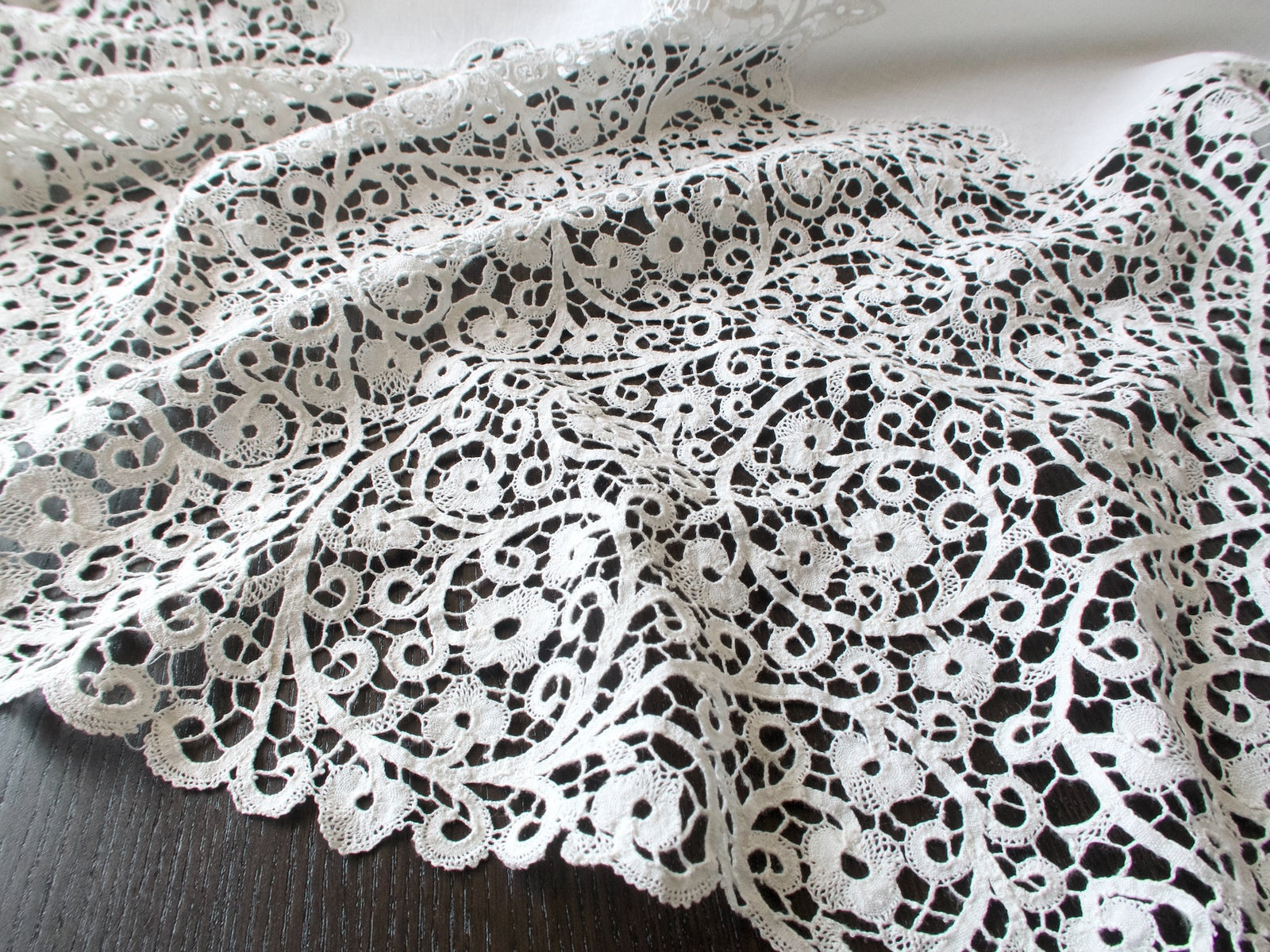Close-up of the handmade Cantù lace on a vintage Italian round tablecloth.