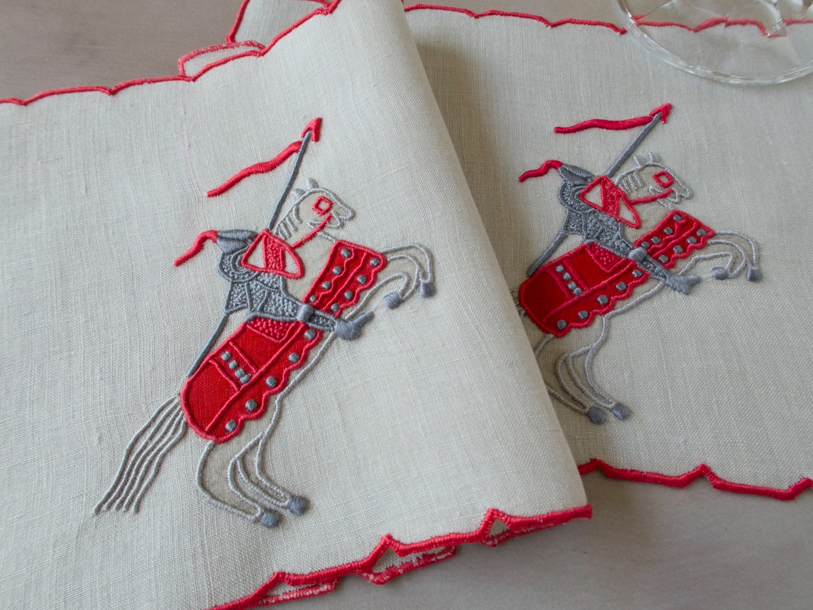 Vintage Marghab Knight pattern cocktail napkins, red embroidery on oyster-colored linen showing knight on horseback, handmade in Madeira.