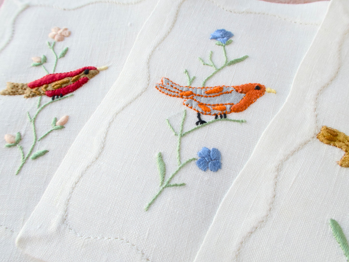 Vintage Madeira embroidered linen cocktail napkin with colorful red bird perched on flowering branch with blue blossoms