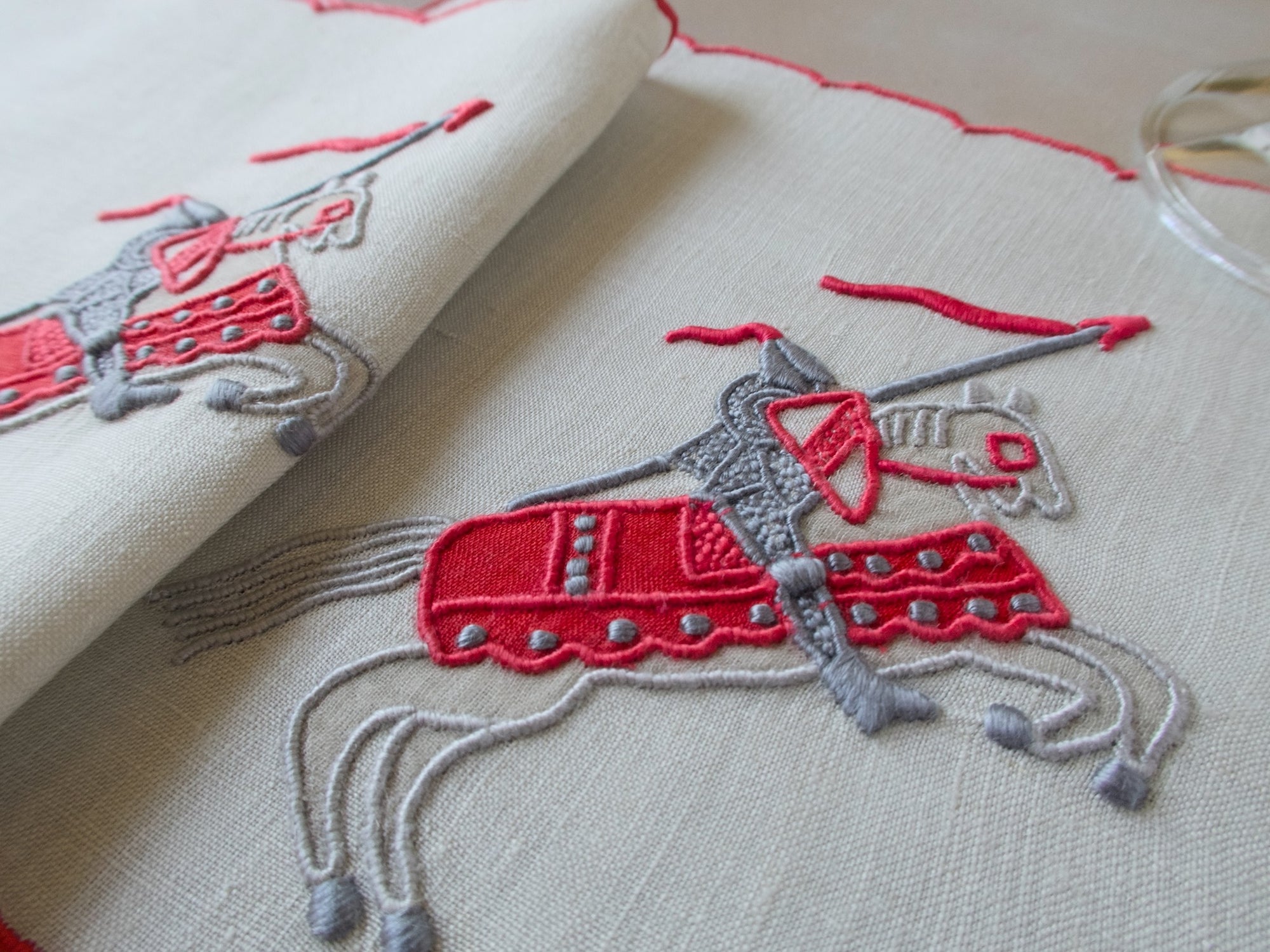 Vintage Marghab Knight pattern cocktail napkins, red embroidery on oyster-colored linen showing knight on horseback, handmade in Madeira.