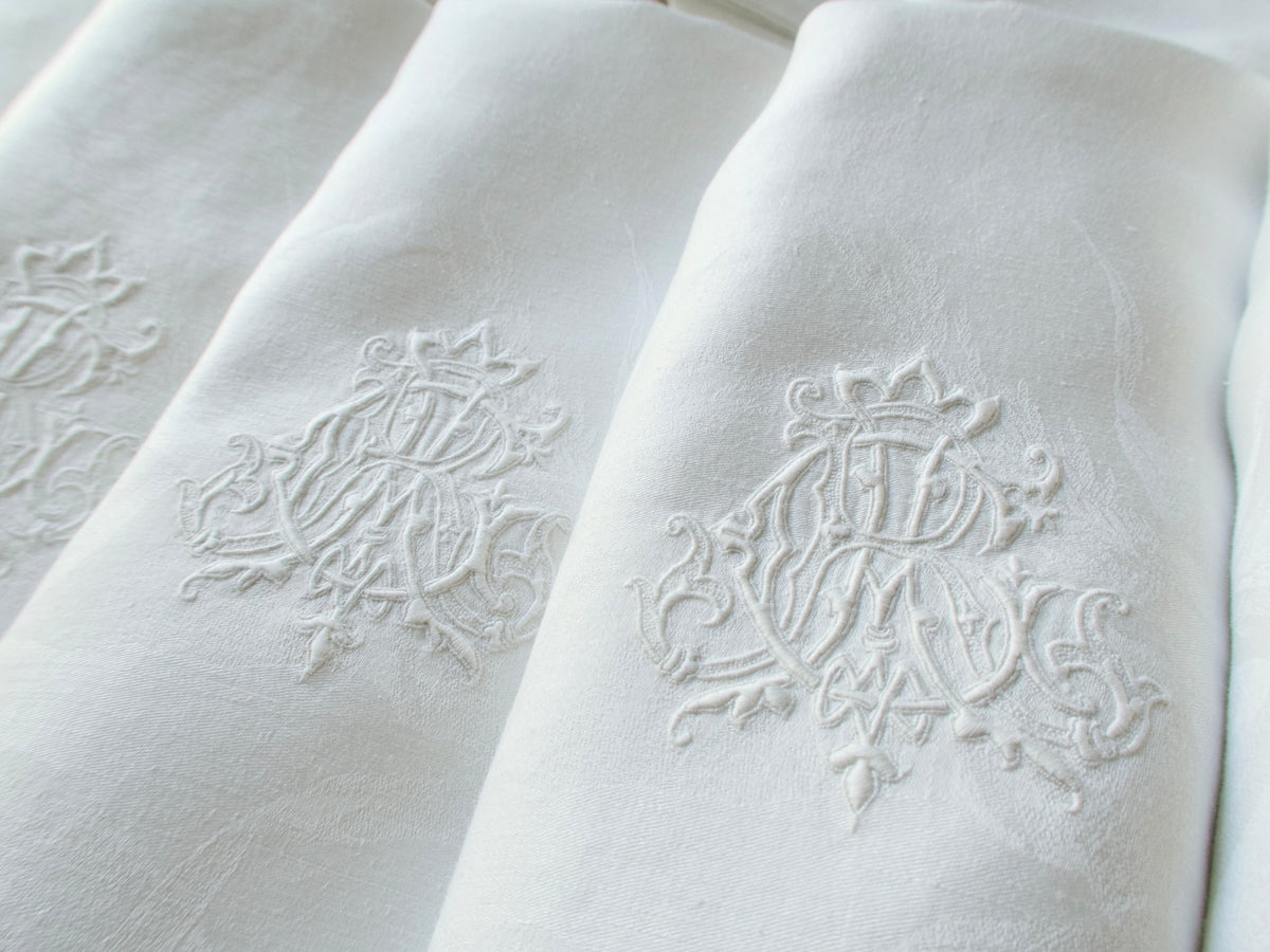 Two antique damask linen napkins folded to show a hand embroidered triple monogram ACR