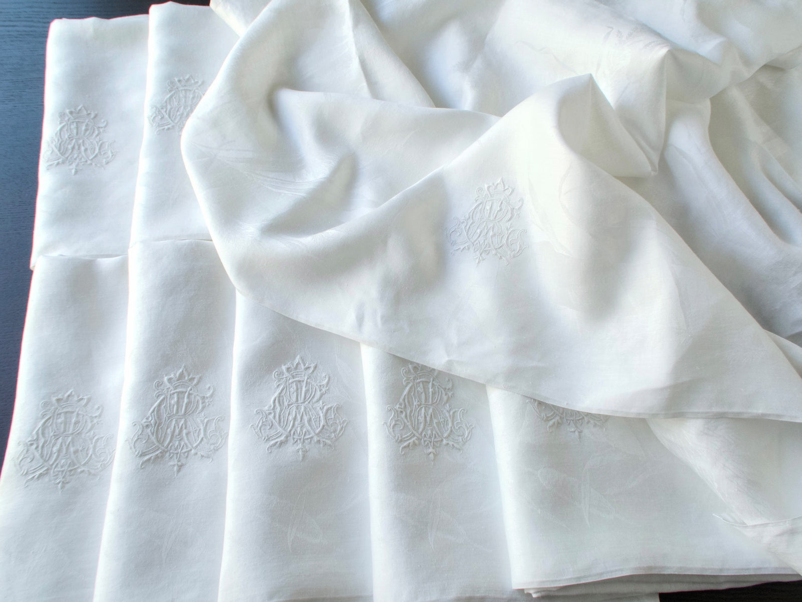 Antique damask linen napkins draped to show the embroidered ACR monograms across several pieces