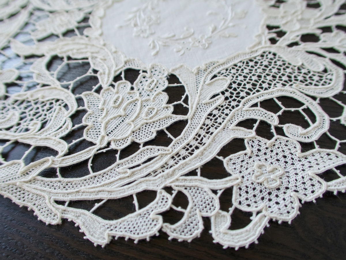 Close view of Point de Venise lace florals and openwork on an antique round placemat