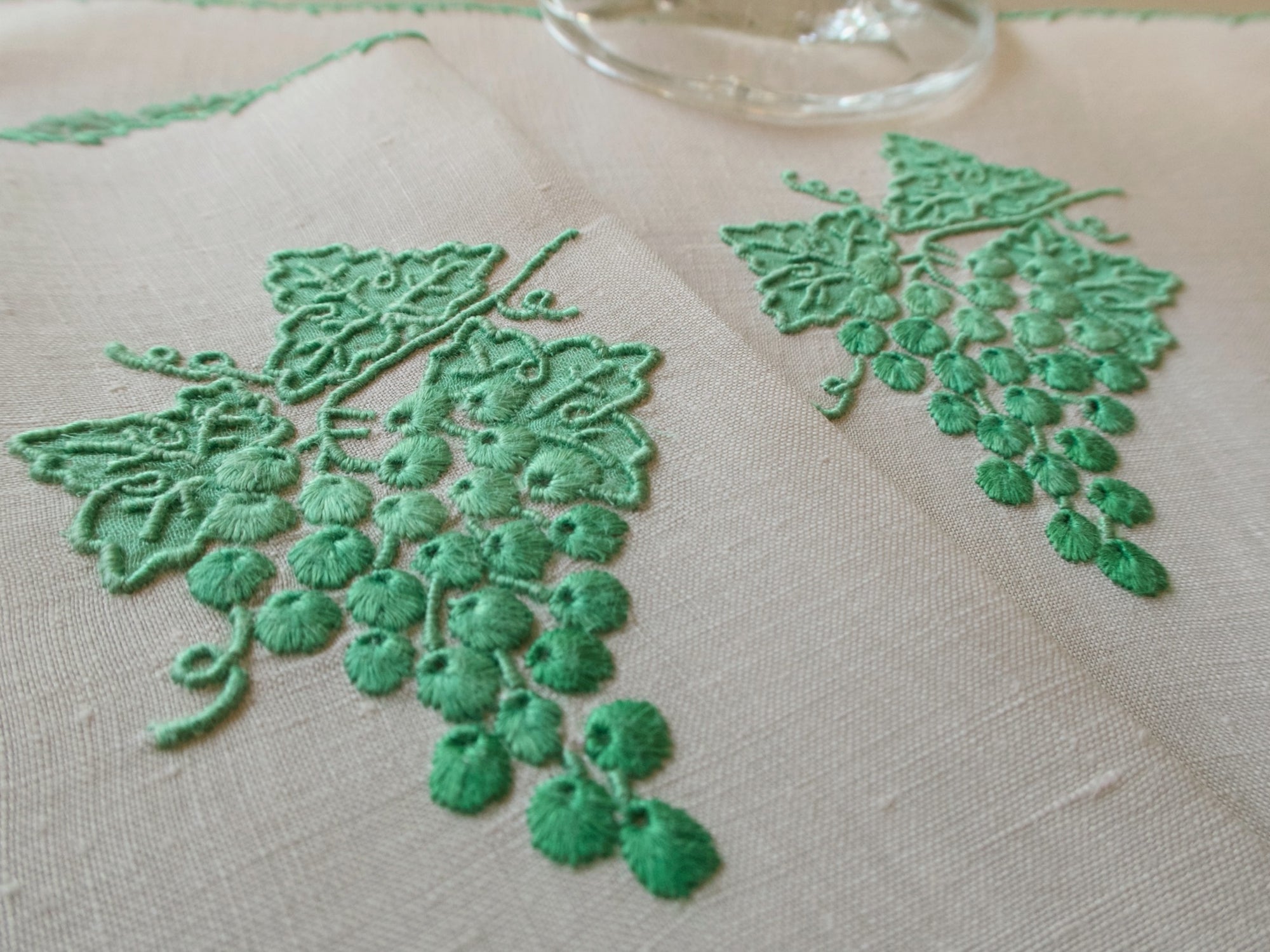Detail of vintage Marghab Grape & Leaf cocktail napkins, green hand embroidery on linen with grape cluster motif, handmade in Madeira.