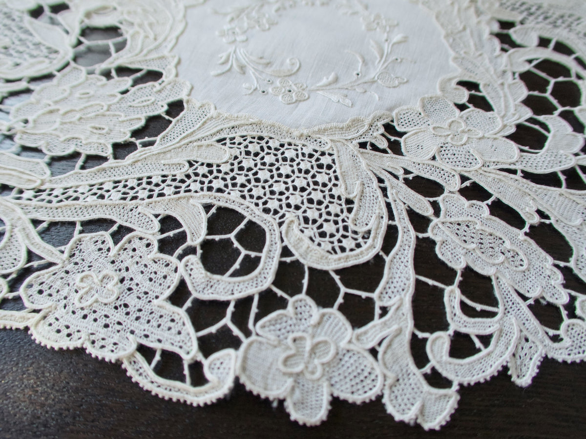 Close view of Point de Venise needle lace border on an antique linen placemat showing varied filler stitches