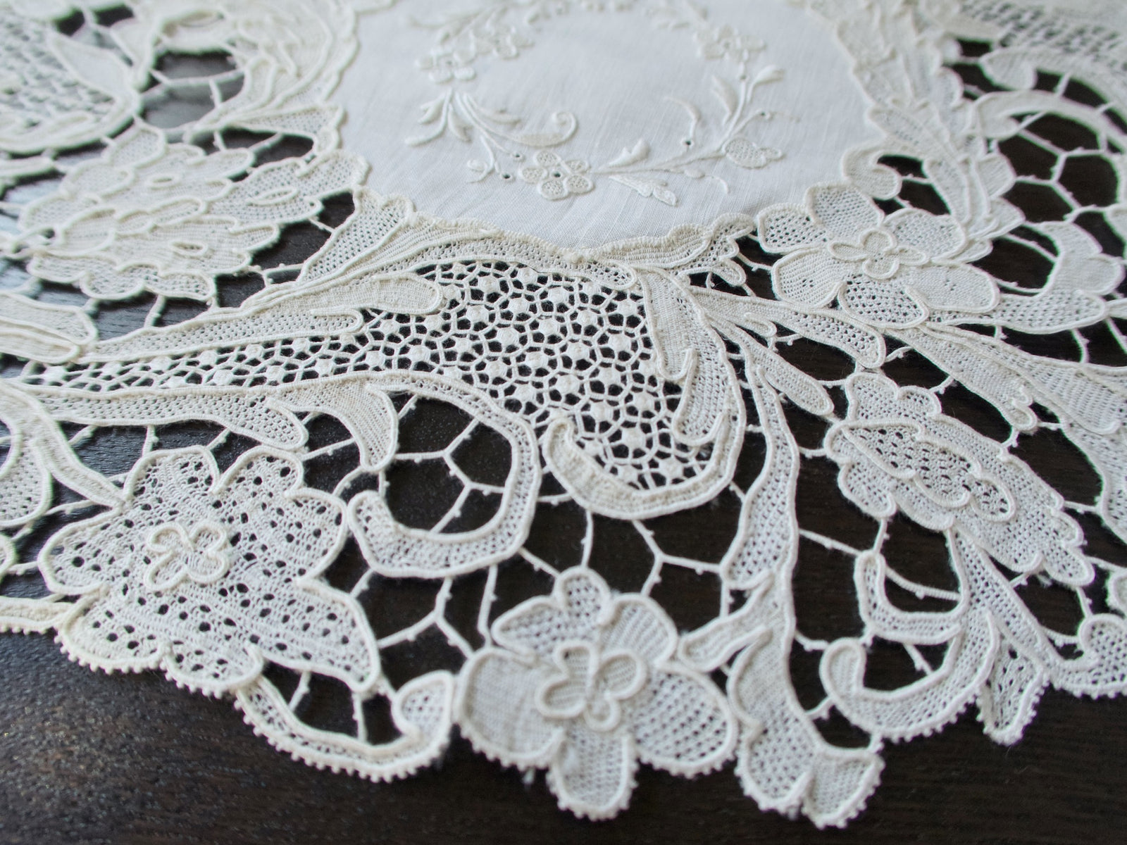 Close view of Point de Venise needle lace border on an antique linen placemat showing varied filler stitches