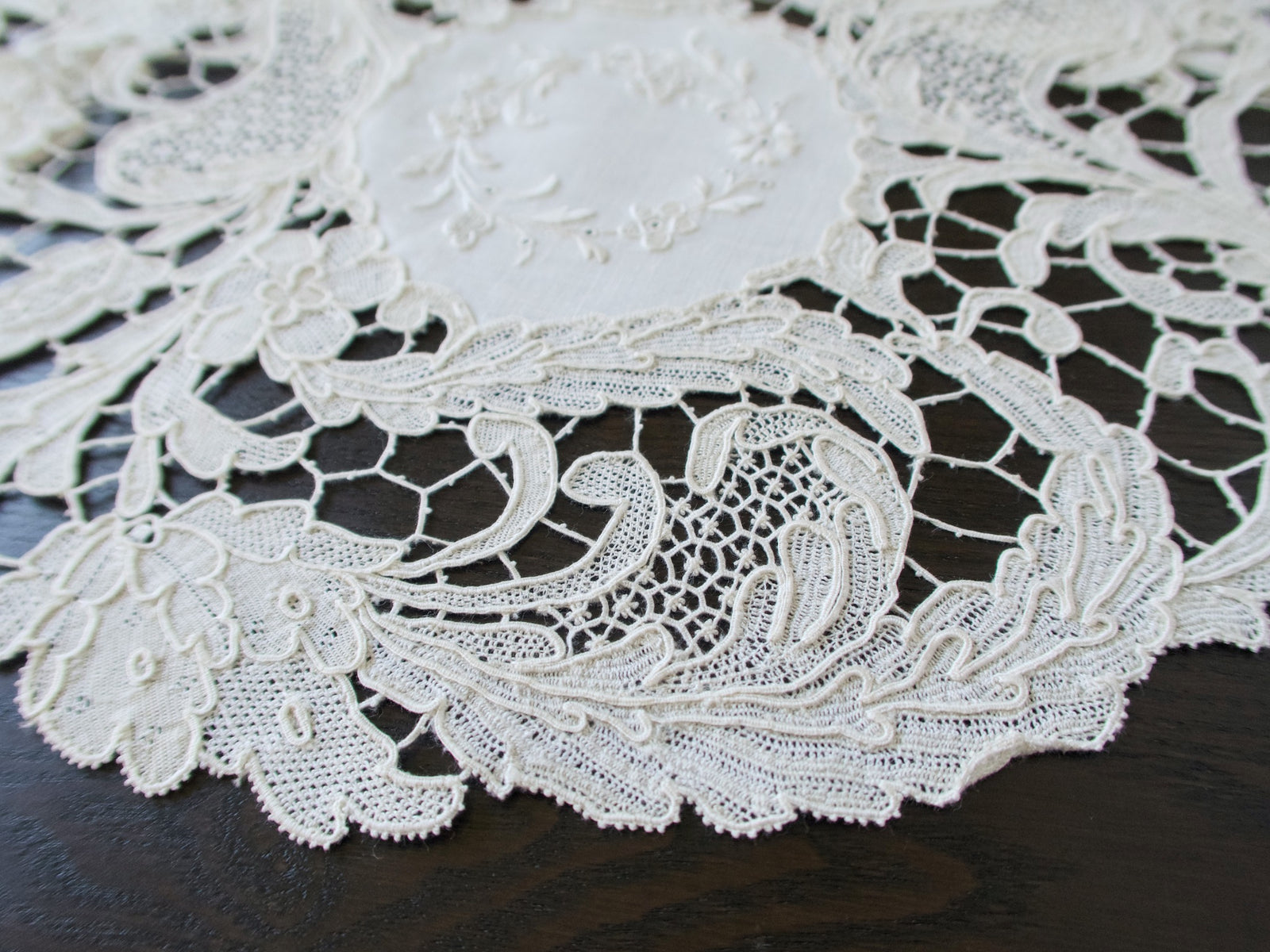 Close view of Point de Venise lace florals and openwork on an antique round placemat