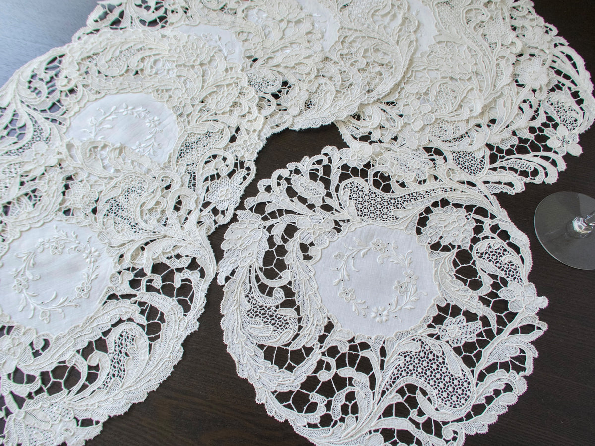 Antique Point de Venise lace placemats overlapping to show the dense floral needle lace border