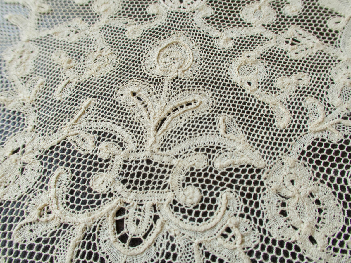 Close view of the Milanese lace center on an antique placemat, floral motifs worked on fine net