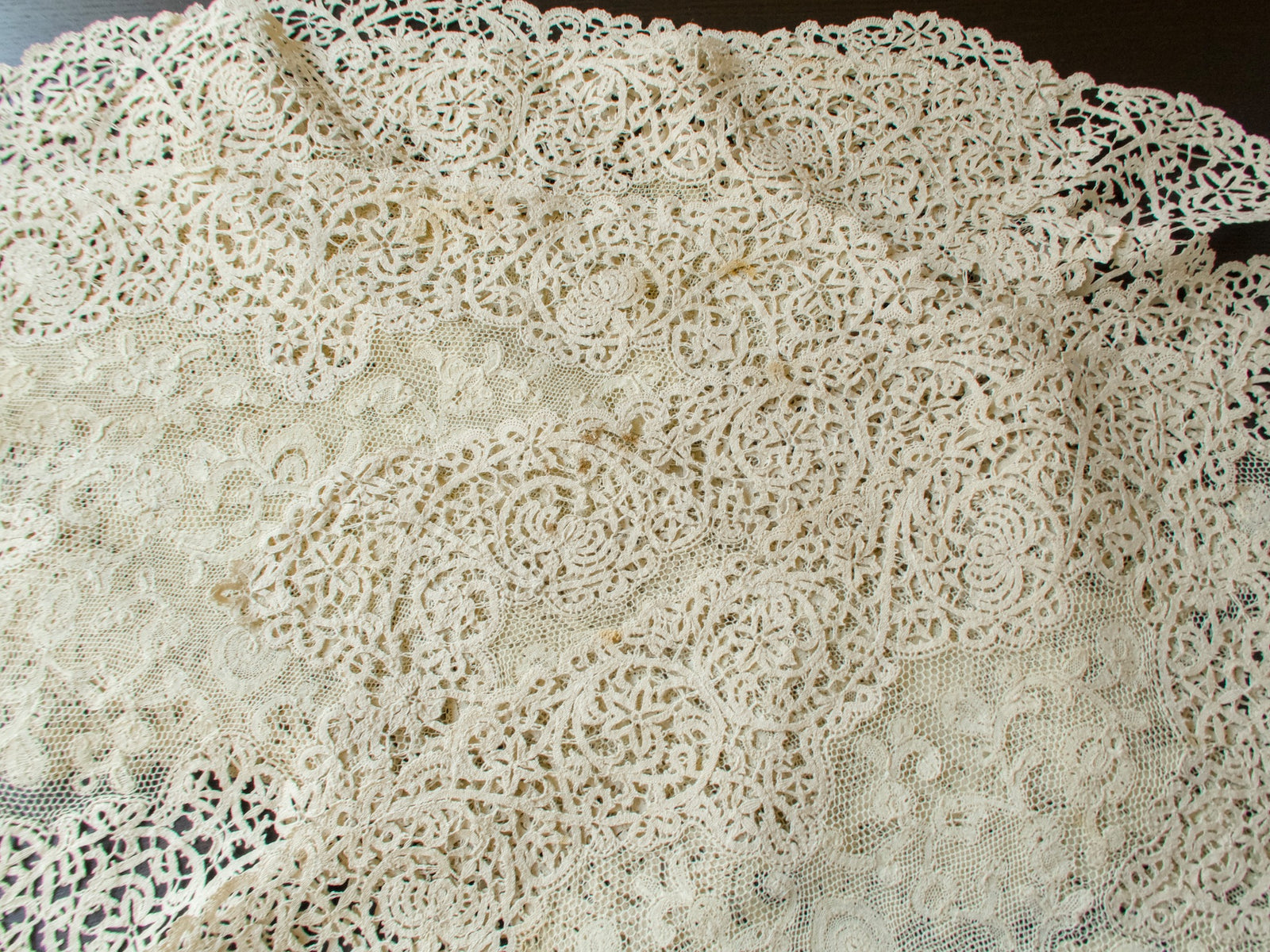 Antique lace placemats overlapping, showing a few remaining storage spots in the bobbin lace