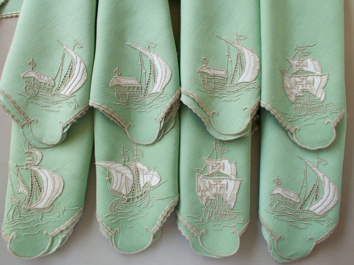 Vintage Marghab “Old Ships” placemat and napkin set, hand embroidered in Madeira on fine Irish linen in sea-green tones, featuring ships, waves, and mythical sea creatures in intricate raised embroidery.
