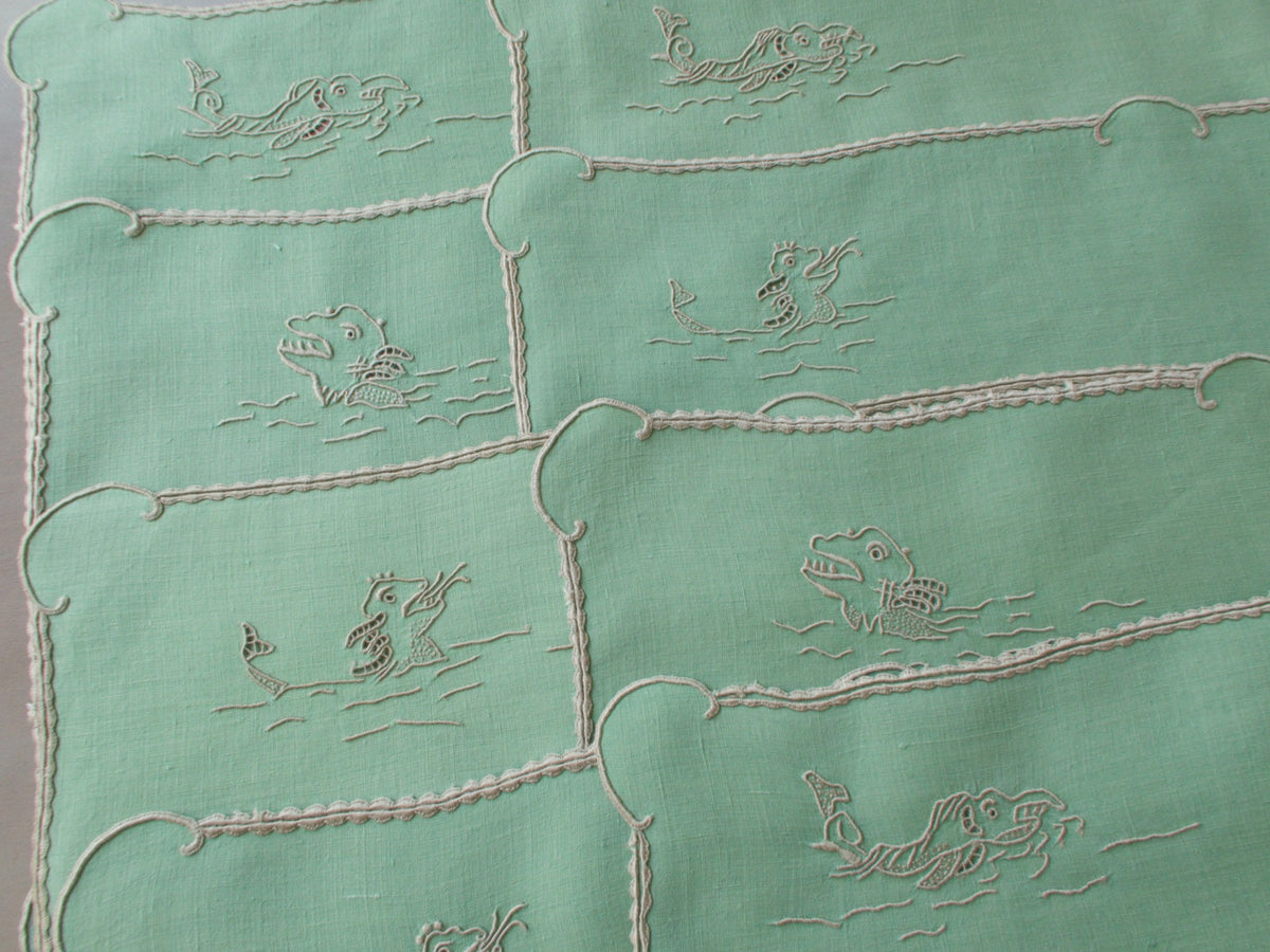 Vintage Marghab “Old Ships” placemat and napkin set, hand embroidered in Madeira on fine Irish linen in sea-green tones, featuring ships, waves, and mythical sea creatures in intricate raised embroidery.