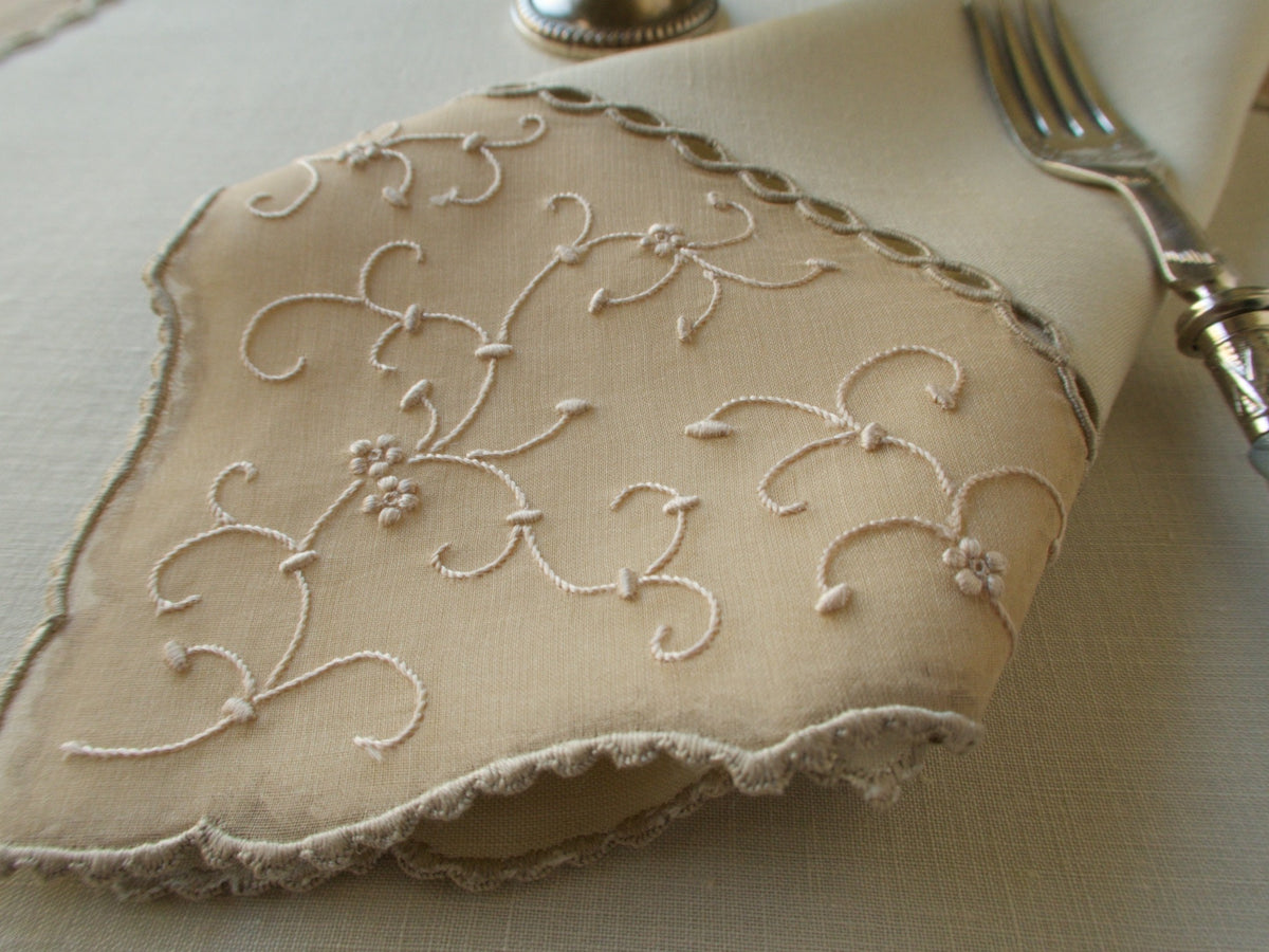 Detail from  Marghab&#39;s “Open Lacing” placemat and napkin set, hand embroidered in Madeira on fine linen and organdy with tone-on-tone floral motifs and delicate caseado bastido edges.