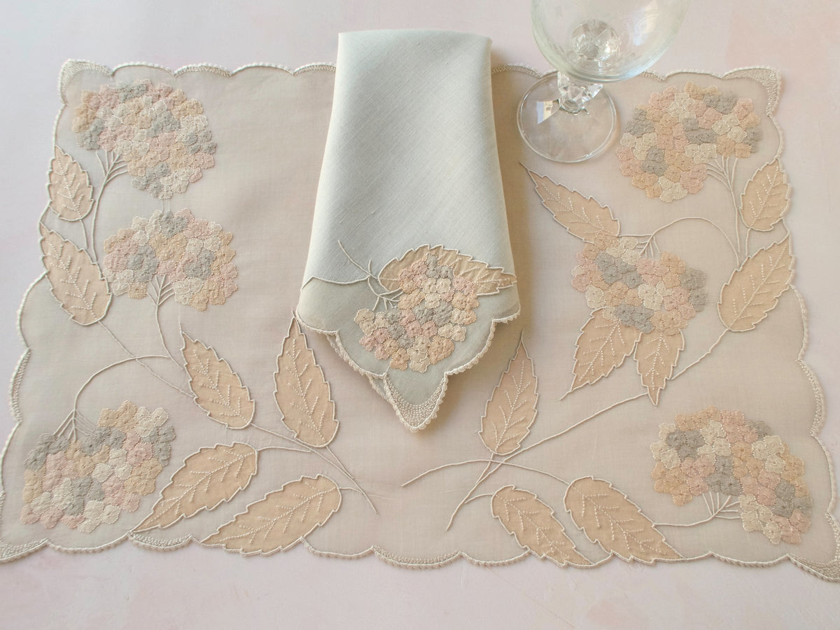 Vintage Marghab “Hydrangea” placemat and napkin set, hand embroidered in Madeira on fine organdy and linen, featuring intricate hydrangea blossoms in soft shades of cream and beige.