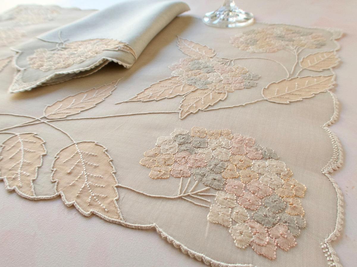 Vintage Marghab “Hydrangea” placemat and napkin set, hand embroidered in Madeira on fine organdy and linen, featuring intricate hydrangea blossoms in soft shades of cream and beige.