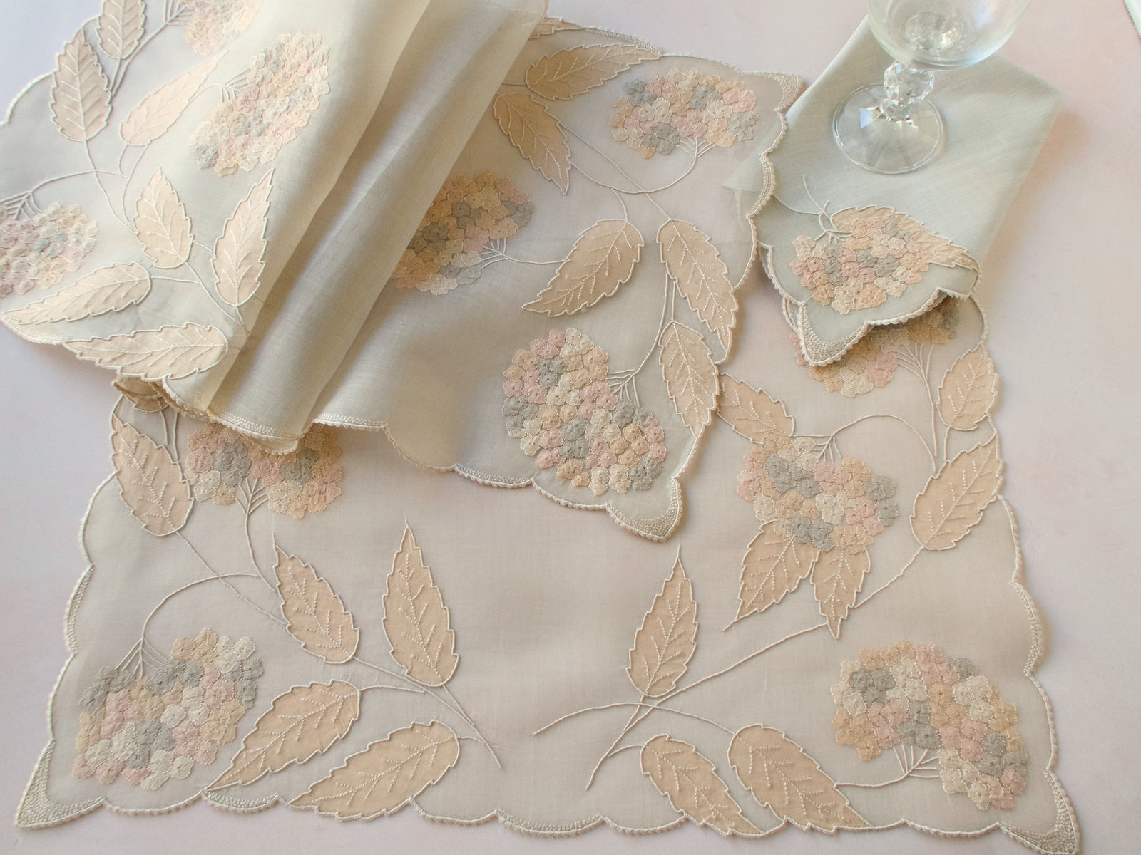 Vintage Marghab “Hydrangea” placemat and napkin set, hand embroidered in Madeira on fine organdy and linen, featuring intricate hydrangea blossoms in soft shades of cream and beige.