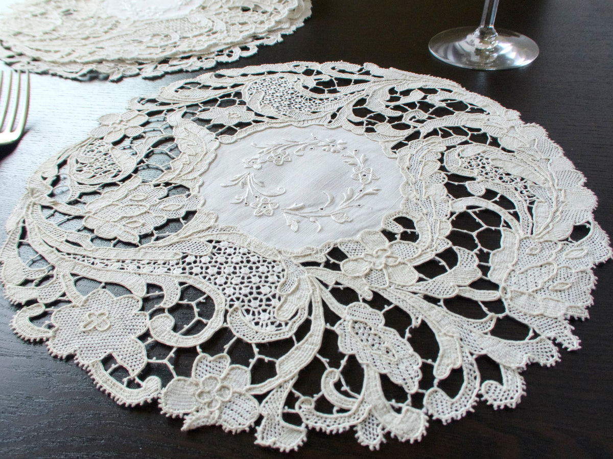 Antique Point de Venise lace placemat with hand embroidered linen center beside a fork and wine glass