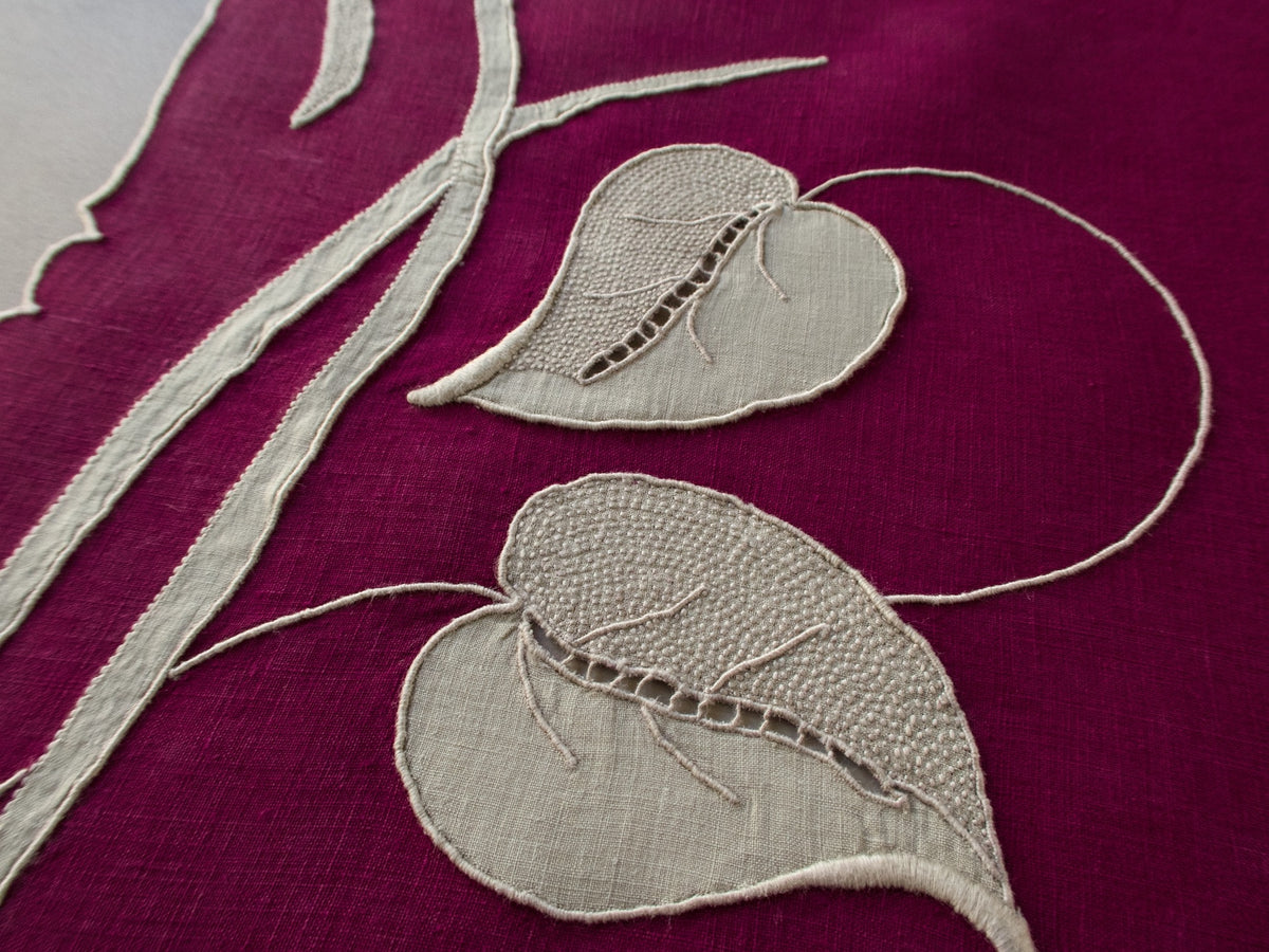 Marghab “Waterleaf” placemat and napkin set in deep plum linen, hand embroidered in Madeira with gray appliqué leaf design.
