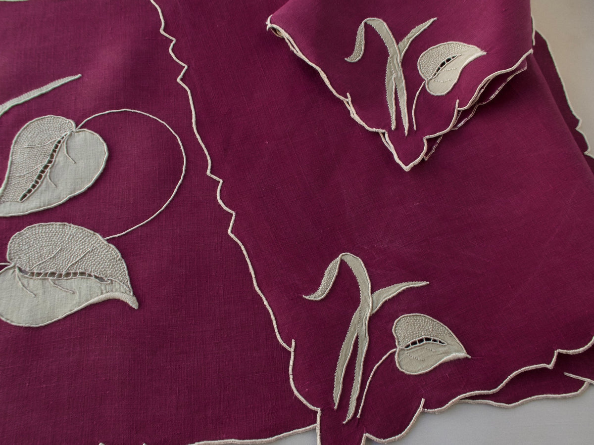 Marghab “Waterleaf” placemat and napkin set in deep plum linen, hand embroidered in Madeira with gray appliqué leaf design.