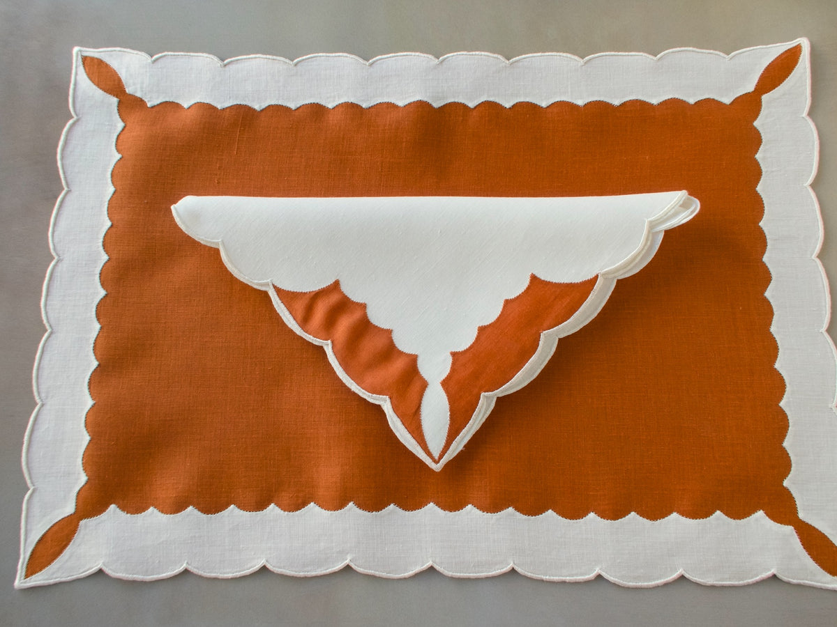 Marghab ‘Minaret’ linen placemat and napkin set in rust and white, hand embroidered in Madeira with bold scalloped appliqué.