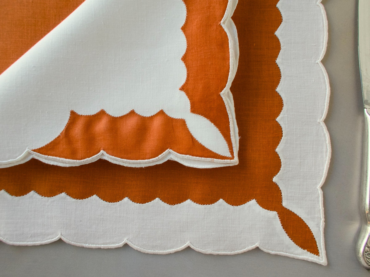 Marghab ‘Minaret’ linen placemat and napkin set in rust and white, hand embroidered in Madeira with bold scalloped appliqué.