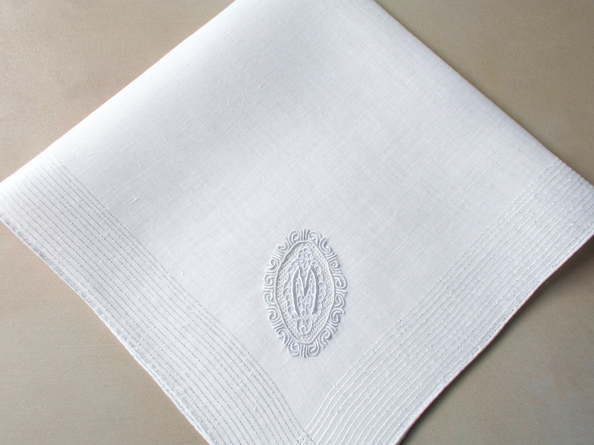 Vintage Marghab handkerchief featuring an “M” monogram in the “Oval Initial” pattern, hand embroidered in white on fine linen. Elegant and beautifully made.