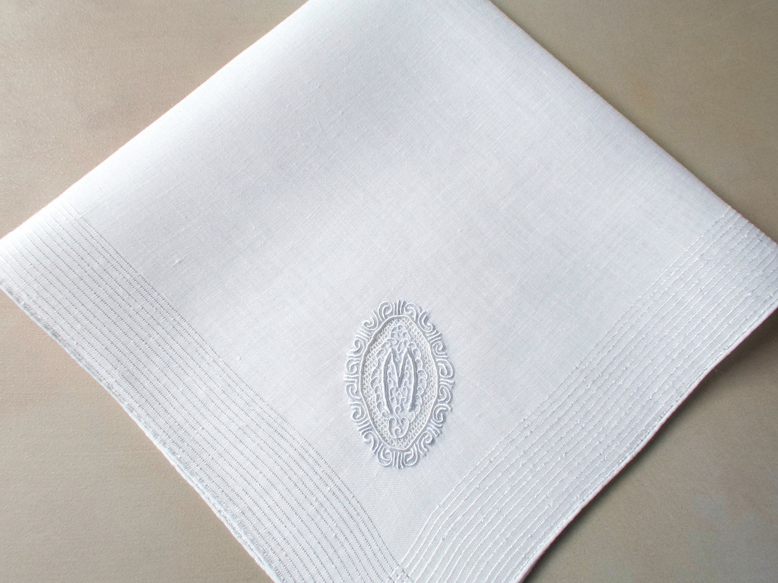 Vintage Marghab handkerchief featuring an “M” monogram in the “Oval Initial” pattern, hand embroidered in white on fine linen. Elegant and beautifully made.
