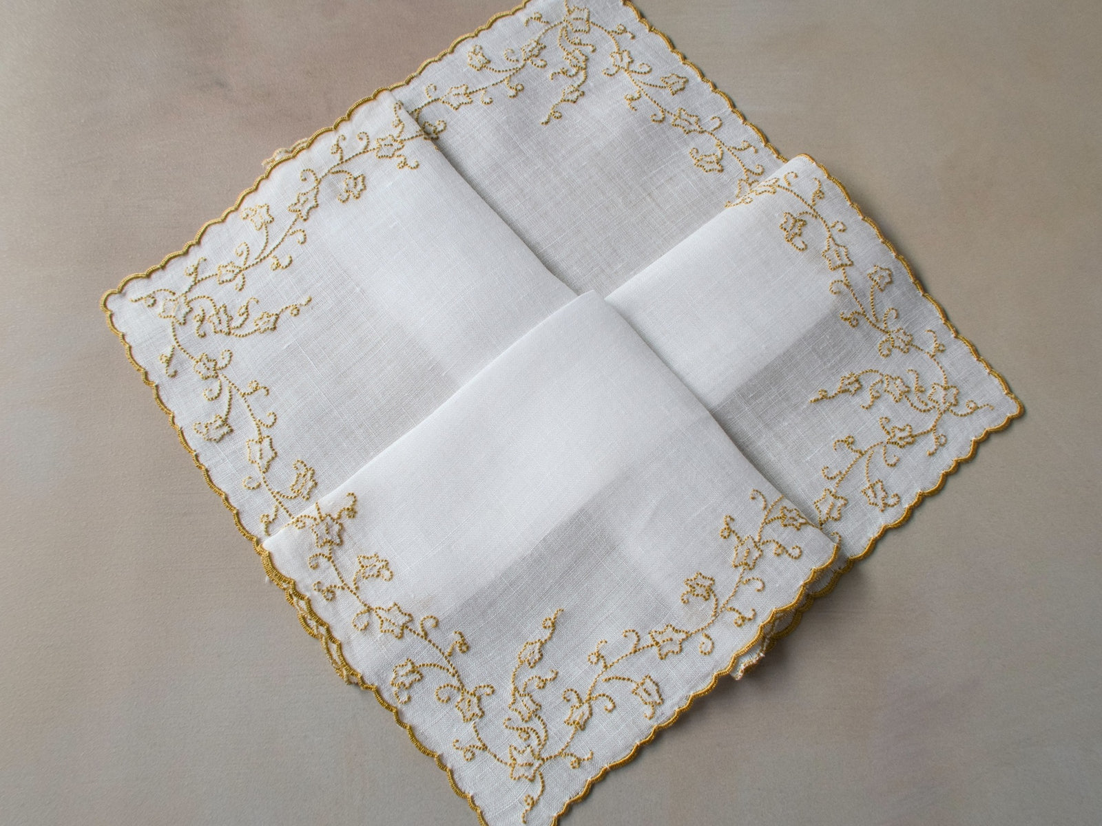 Vintage Marghab “English Ivy” handkerchief, hand embroidered in gold on fine white linen, featuring flowing vine motifs along the scalloped edge.