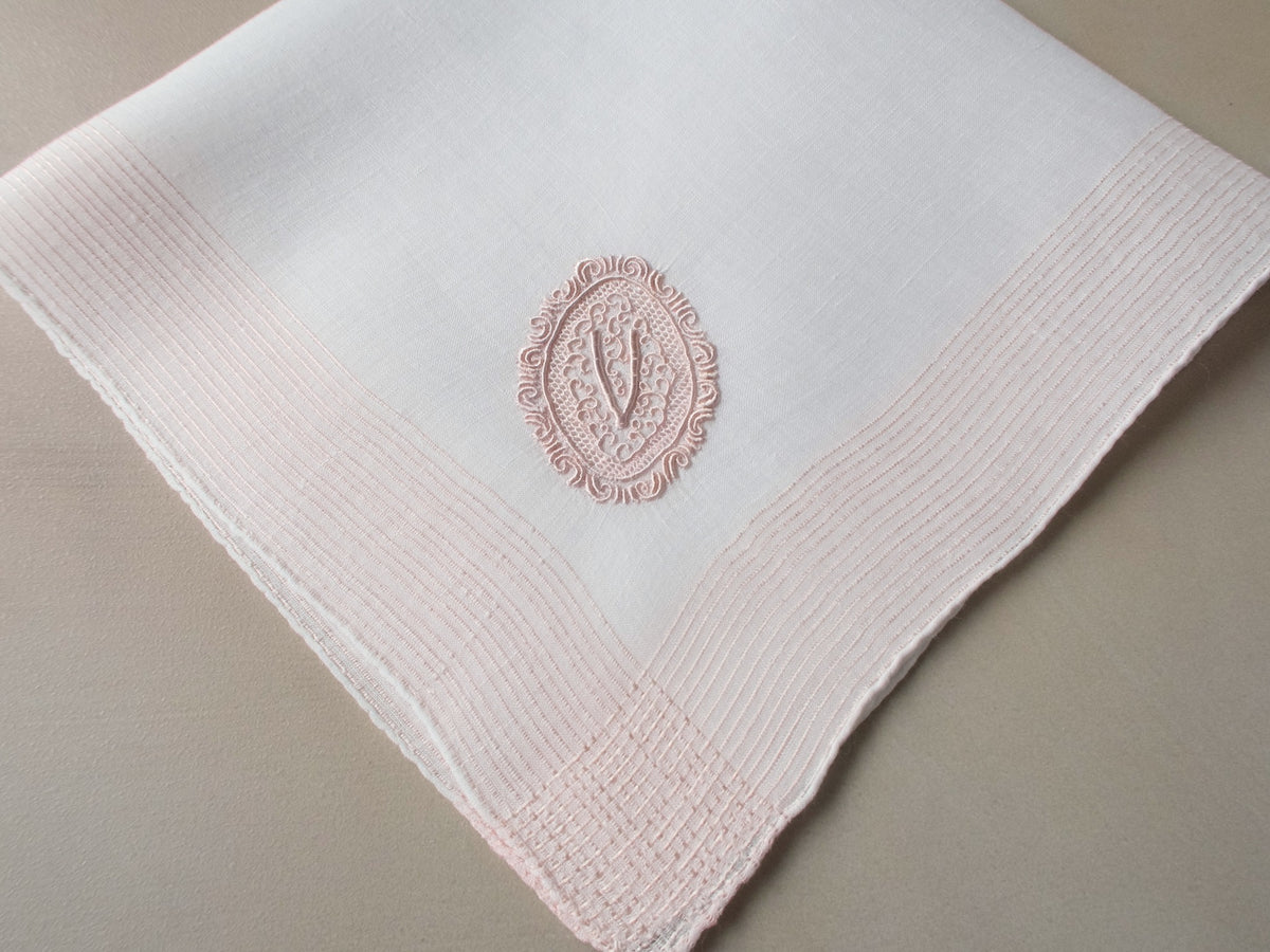Vintage Marghab handkerchief featuring a “V” monogram in the “Oval Initial” pattern, worked in soft pink embroidery on fine linen. Hand embroidered in Madeira.