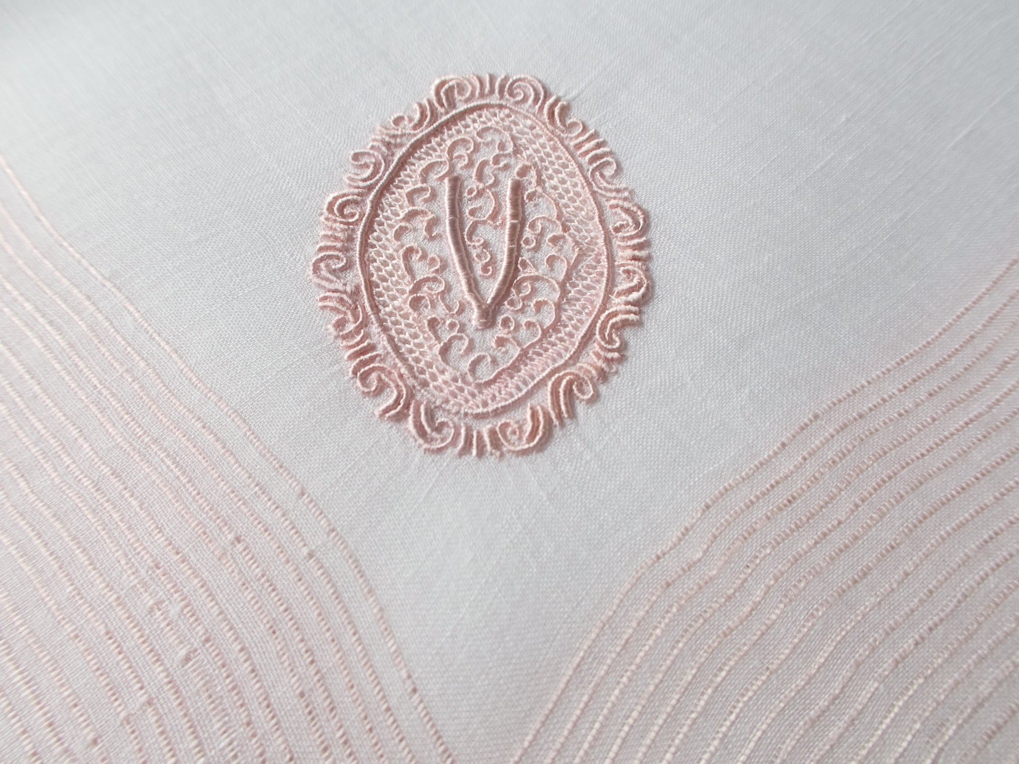 Vintage Marghab handkerchief featuring a “V” monogram in the “Oval Initial” pattern, worked in soft pink embroidery on fine linen. Hand embroidered in Madeira.