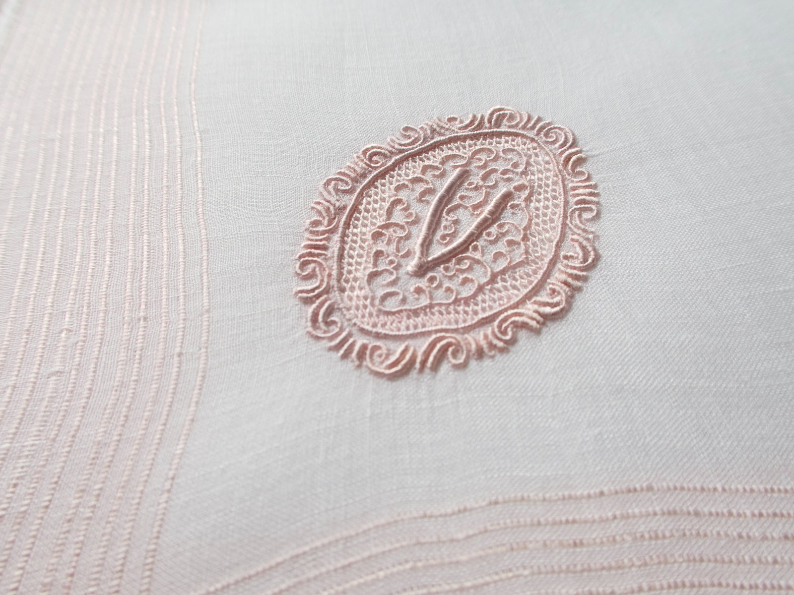 Vintage Marghab handkerchief featuring a “V” monogram in the “Oval Initial” pattern, worked in soft pink embroidery on fine linen. Hand embroidered in Madeira.