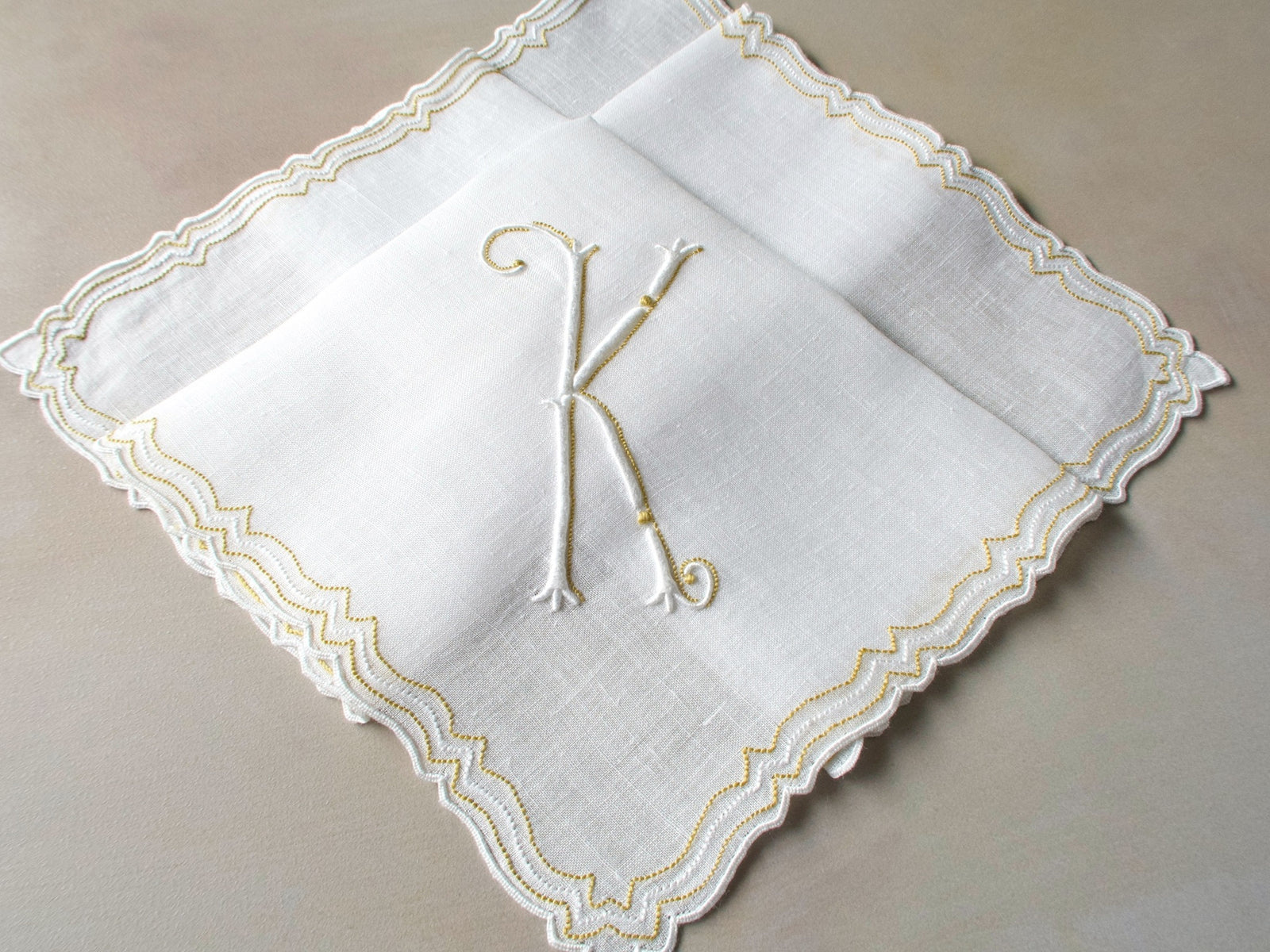 Vintage Marghab handkerchief in the “Initials” pattern, featuring a gold-embroidered “K” monogram with scalloped white border on fine linen. Hand embroidered in Madeira.