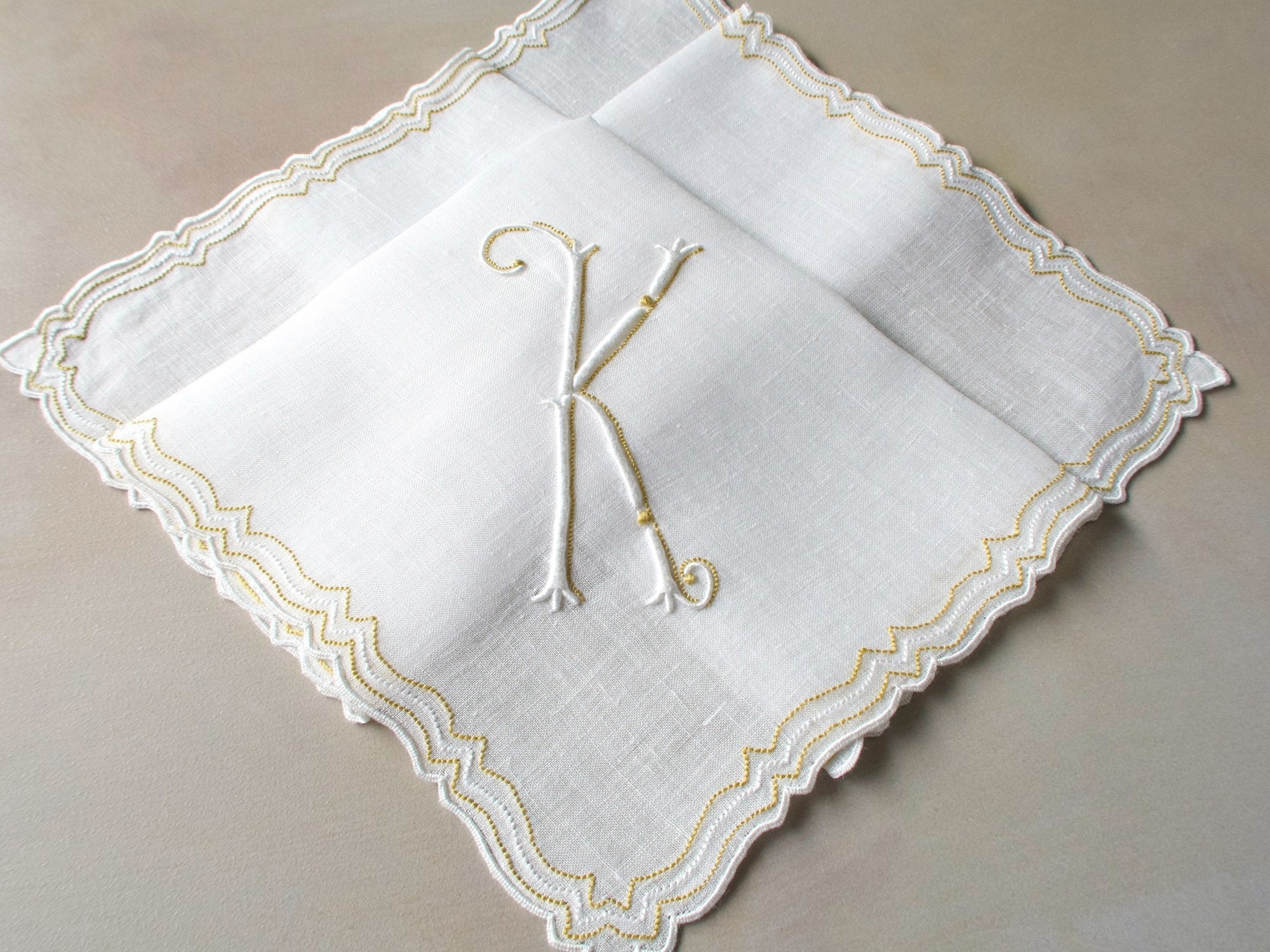Vintage Marghab handkerchief in the “Initials” pattern, featuring a gold-embroidered “K” monogram with scalloped white border on fine linen. Hand embroidered in Madeira.
