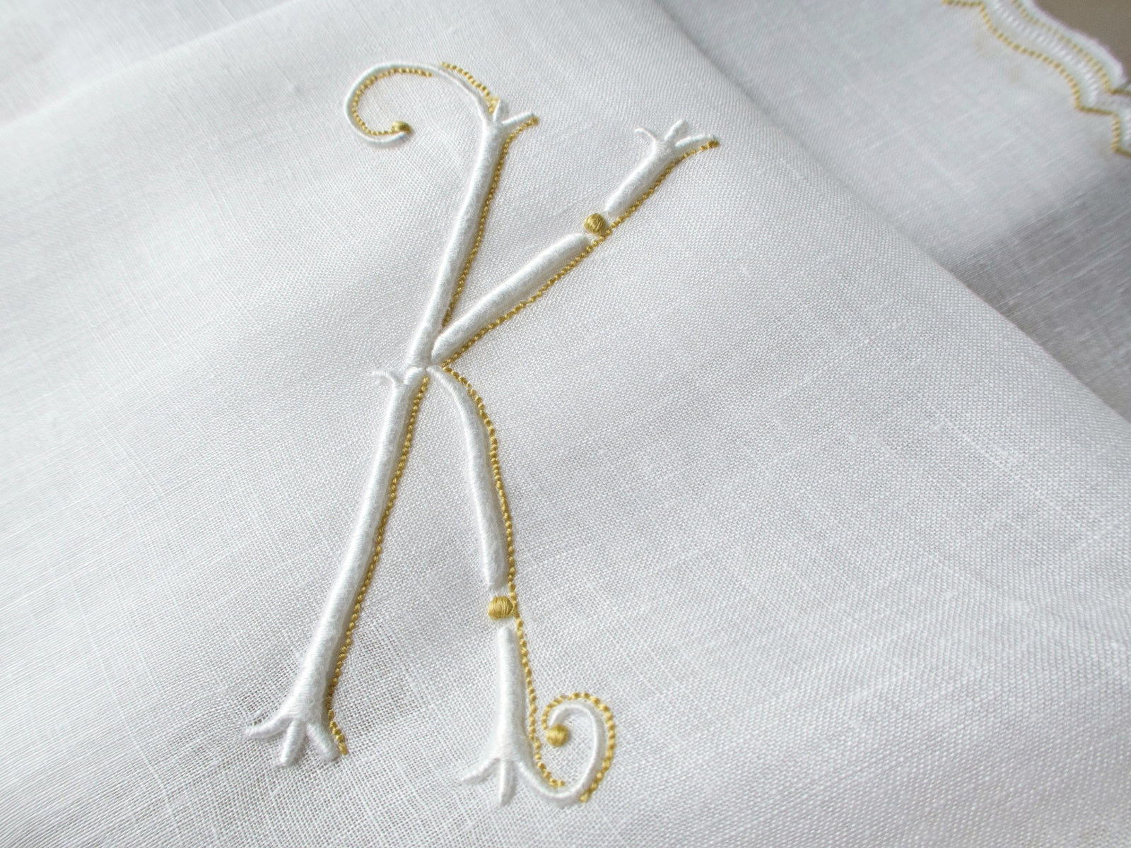 Vintage Marghab handkerchief in the “Initials” pattern, featuring a gold-embroidered “K” monogram with scalloped white border on fine linen. Hand embroidered in Madeira.