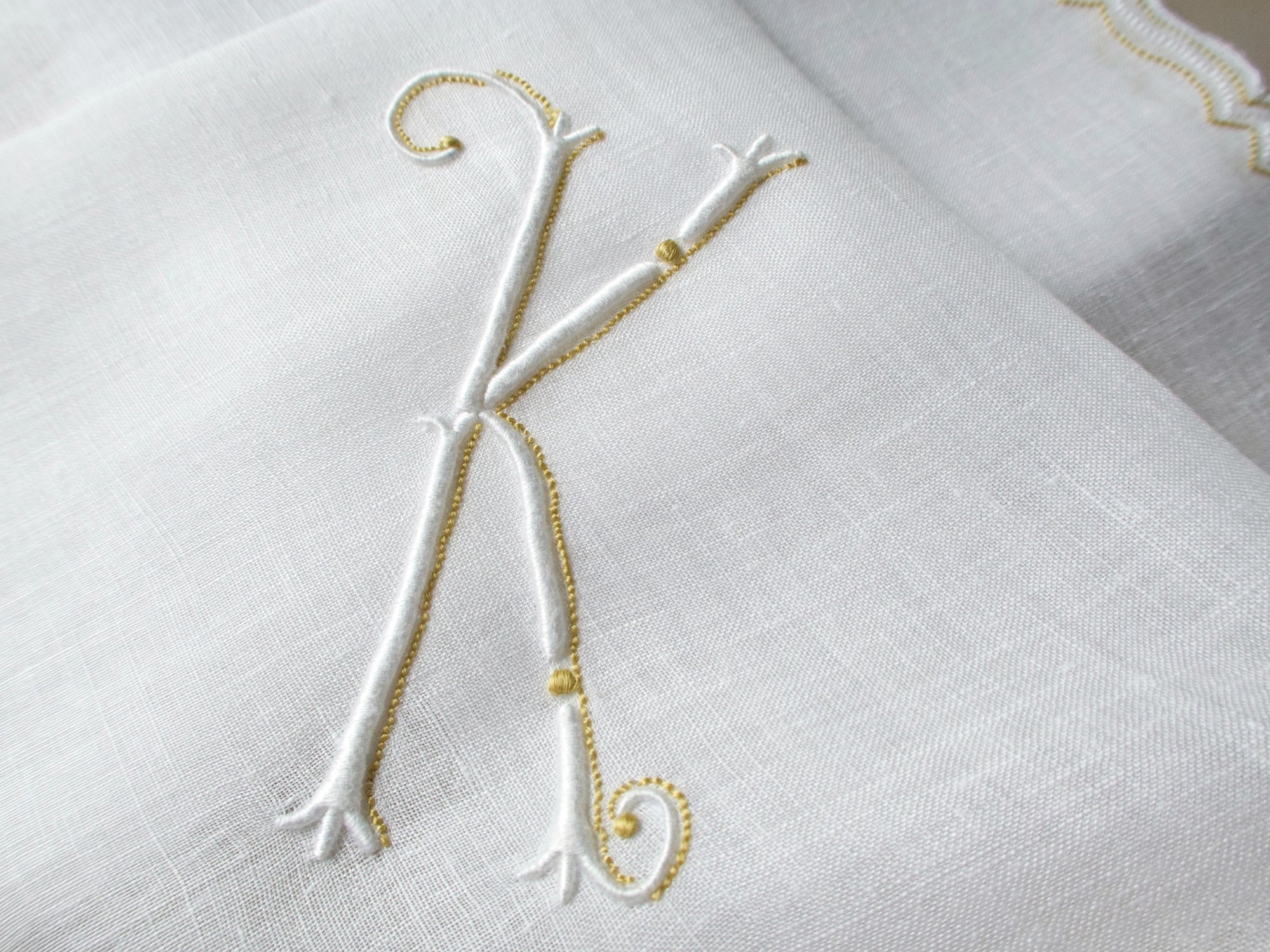 Vintage Marghab handkerchief in the “Initials” pattern, featuring a gold-embroidered “K” monogram with scalloped white border on fine linen. Hand embroidered in Madeira.