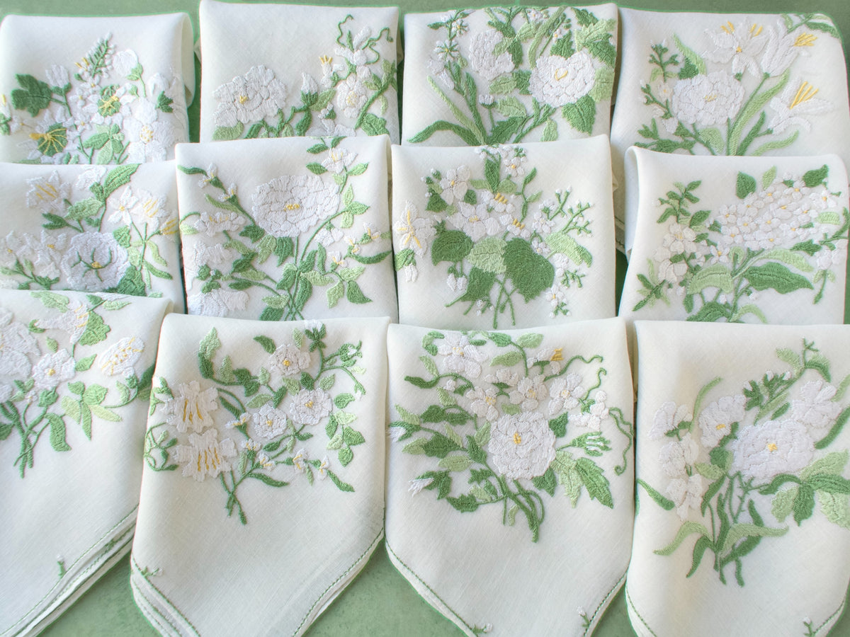 Complete set of twelve Rapisardi napkins arranged in grid, each with different white floral design.