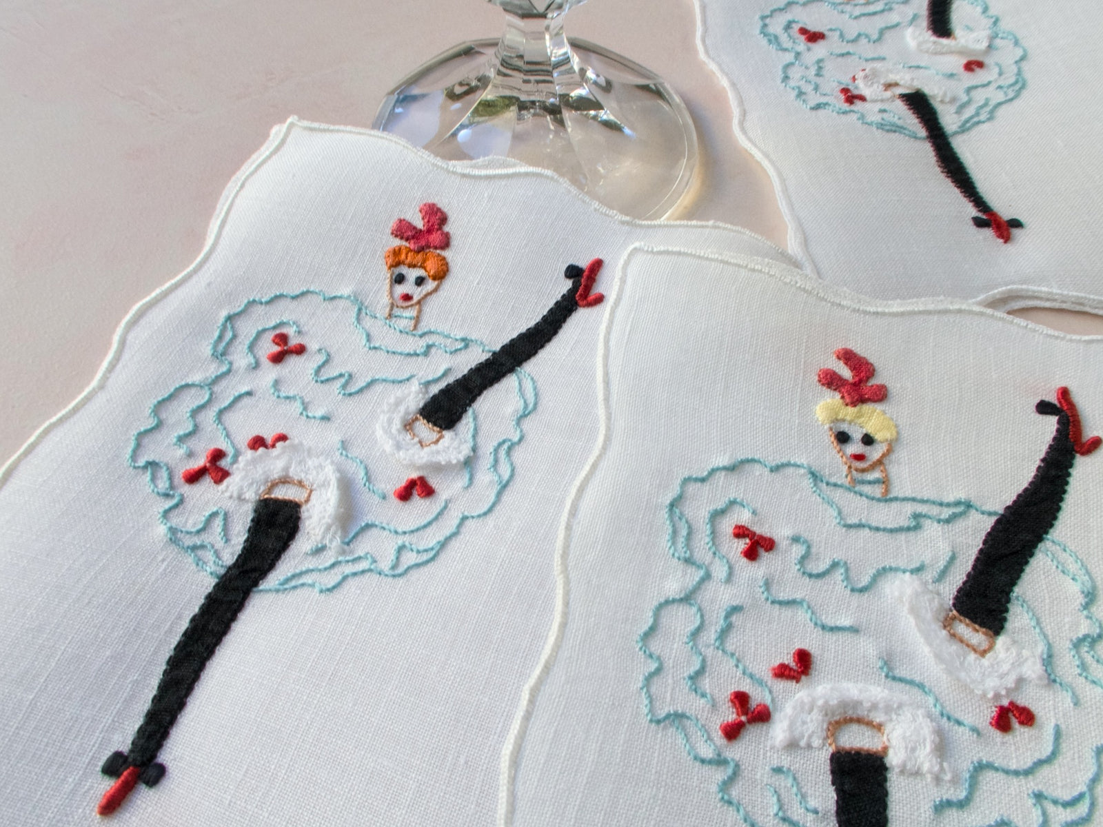 Close-up of embroidered can-can dancer on vintage Madeira napkin with dimensional lace and red details