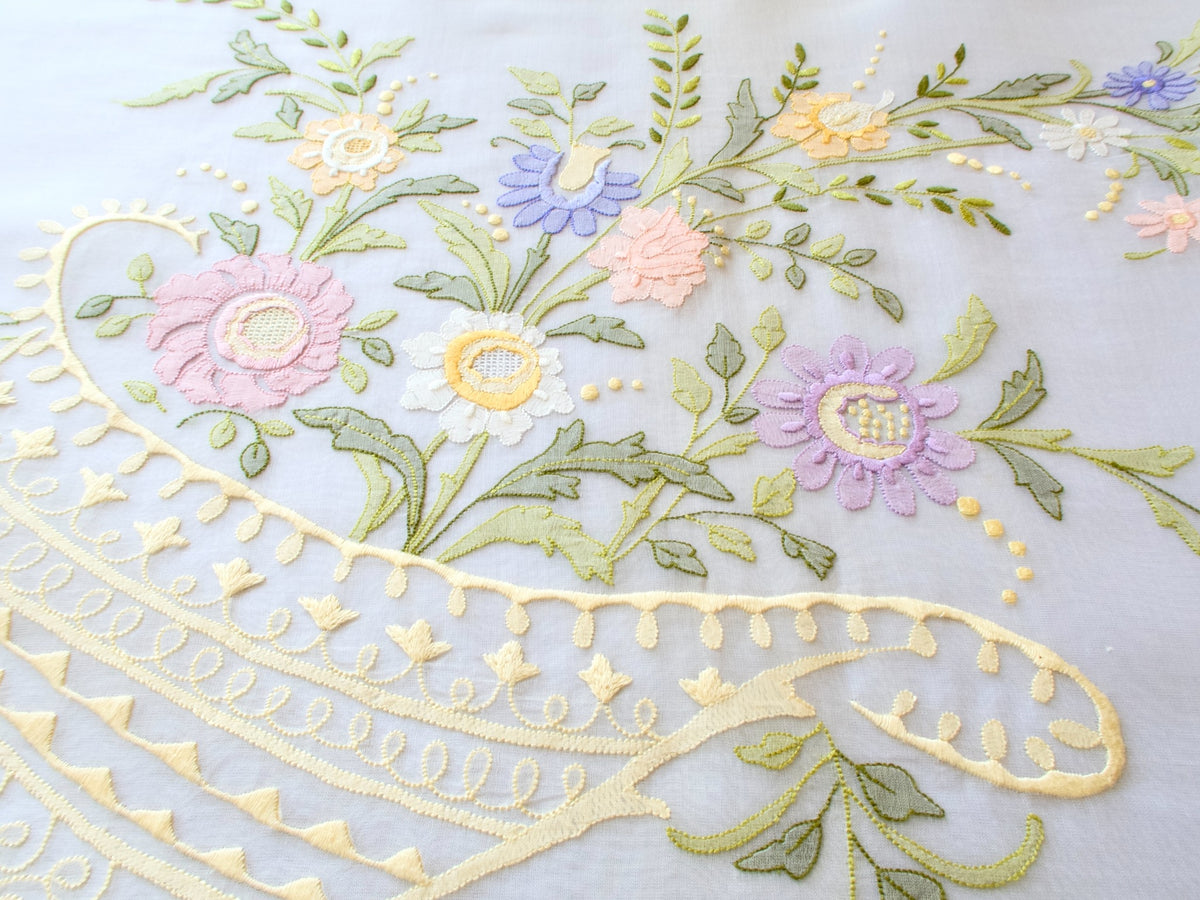 Close-up of floral cornucopia embroidery on vintage organdy tablecloth in pastel shades