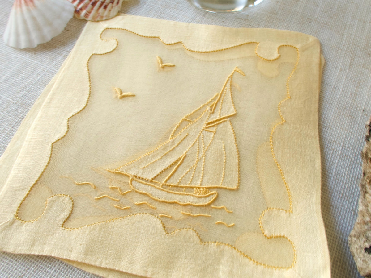 Stack of vintage Madeira sailboat cocktail napkins in yellow linen and organdy showing repliqué border detail