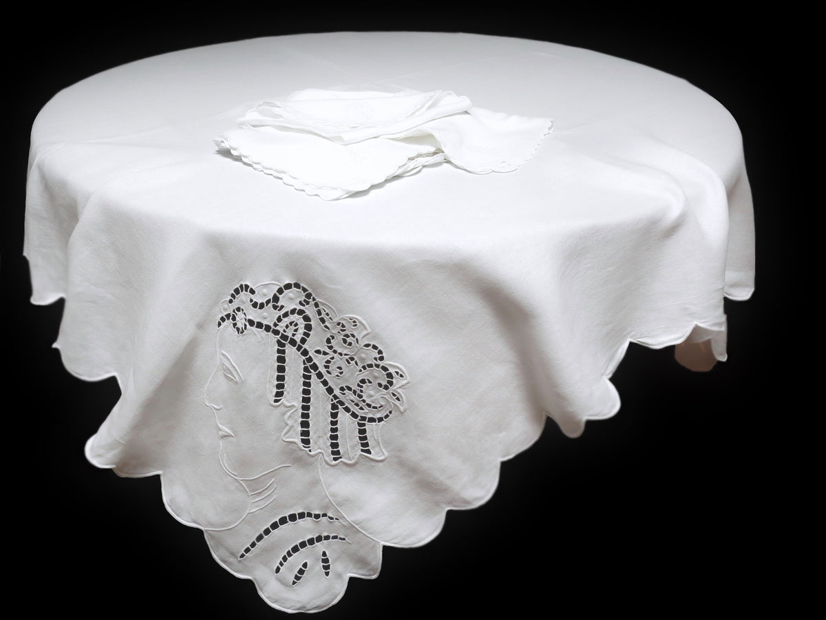 white vintage linen tablecloth ornamented with cutwork figures in classical style