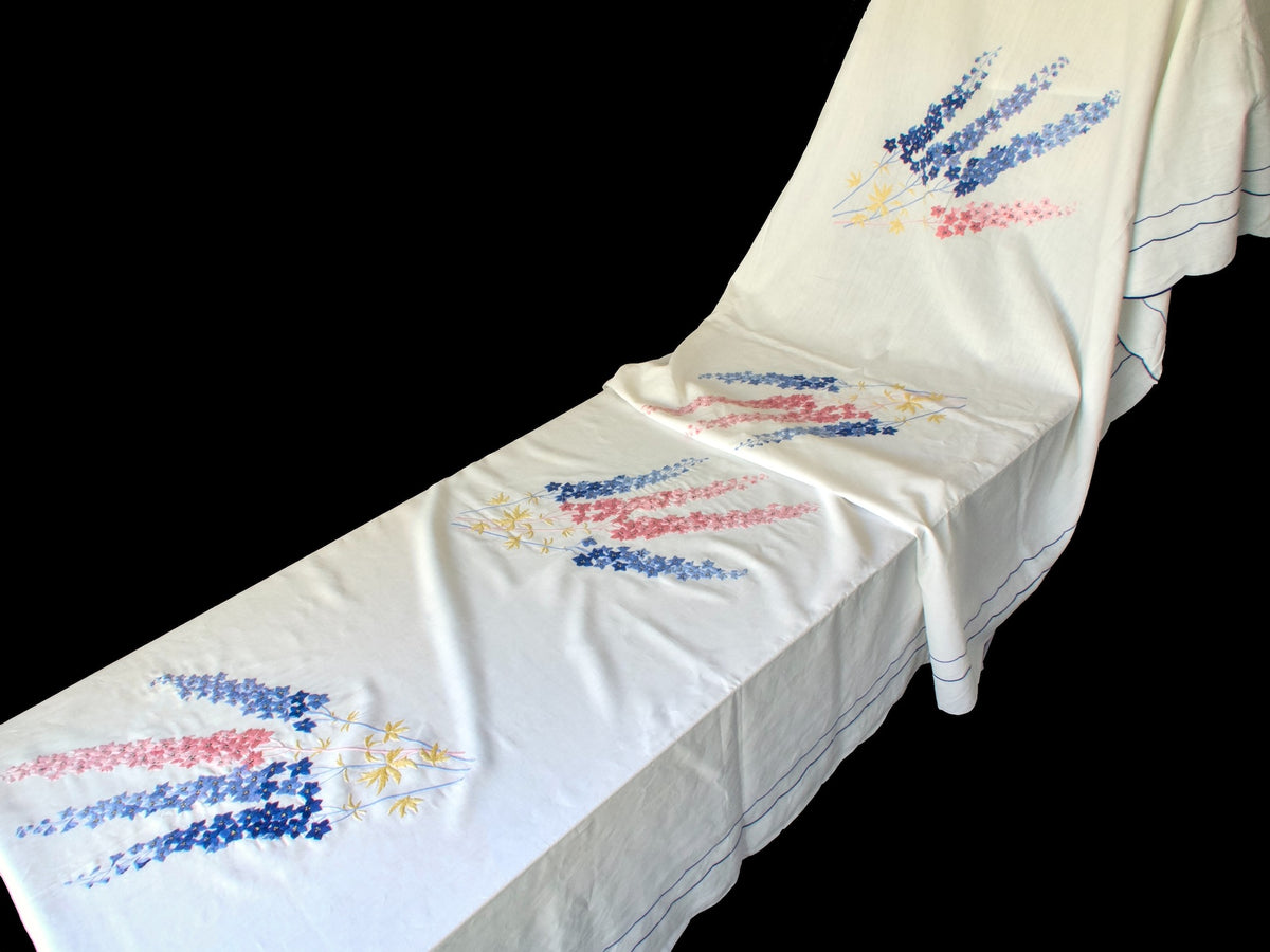 Side view of vintage hand embroidered French banquet tablecloth showing repeated floral motifs across the surface