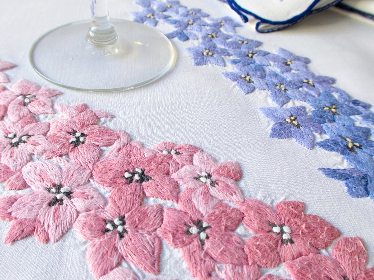 Detail of vintage hand embroidered pink delphinium motifs on French embroidered tablecloth