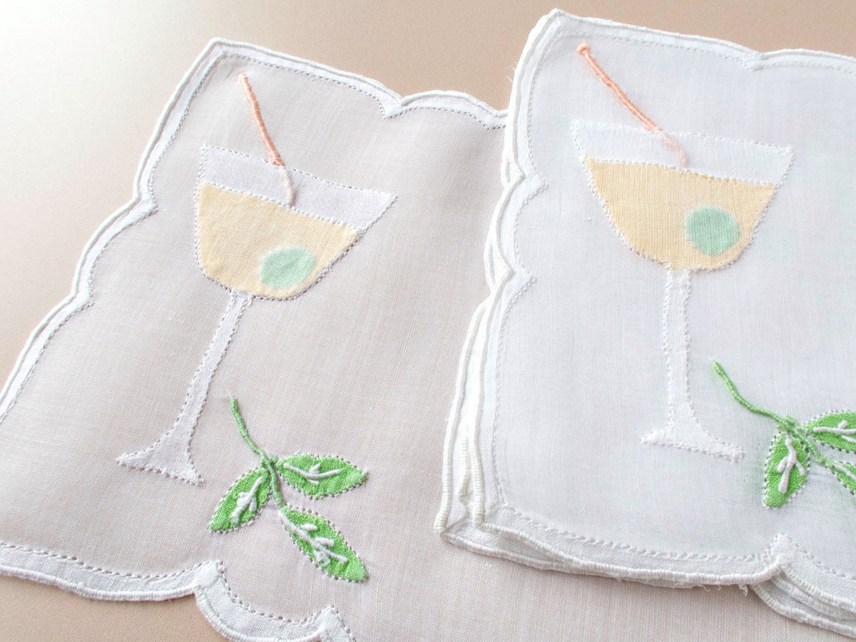 Fanned set of vintage Madeira organdy cocktail napkins showing full martini glass design with shadow appliqué olive and embroidered cocktail pick.